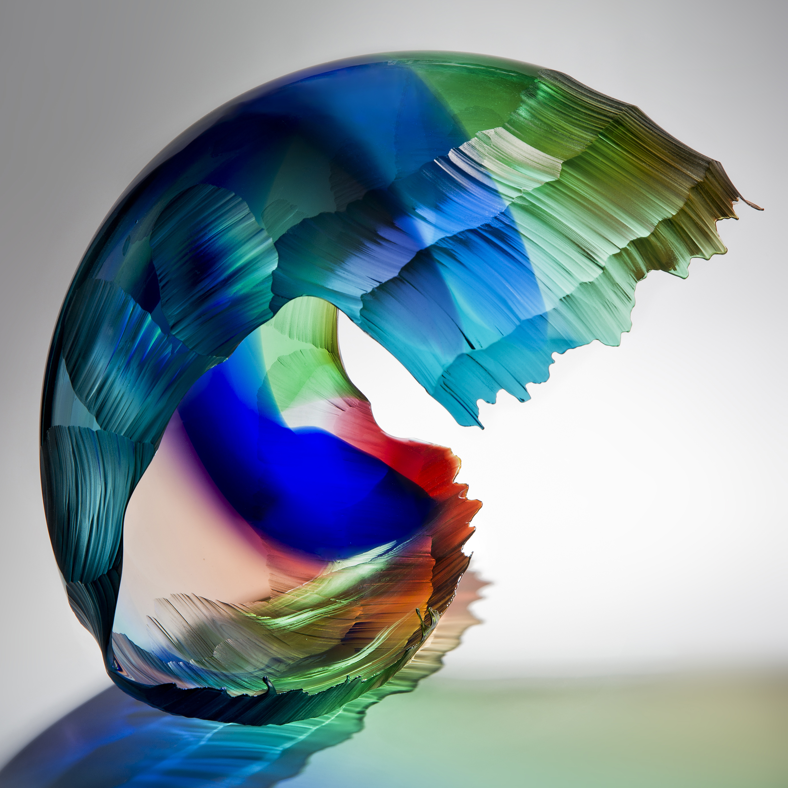 art glass sculpture of wave in bright green blue and red colours