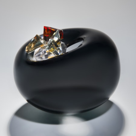 blown glass vase in black in the shape of an apple with red white and gold crystal additions