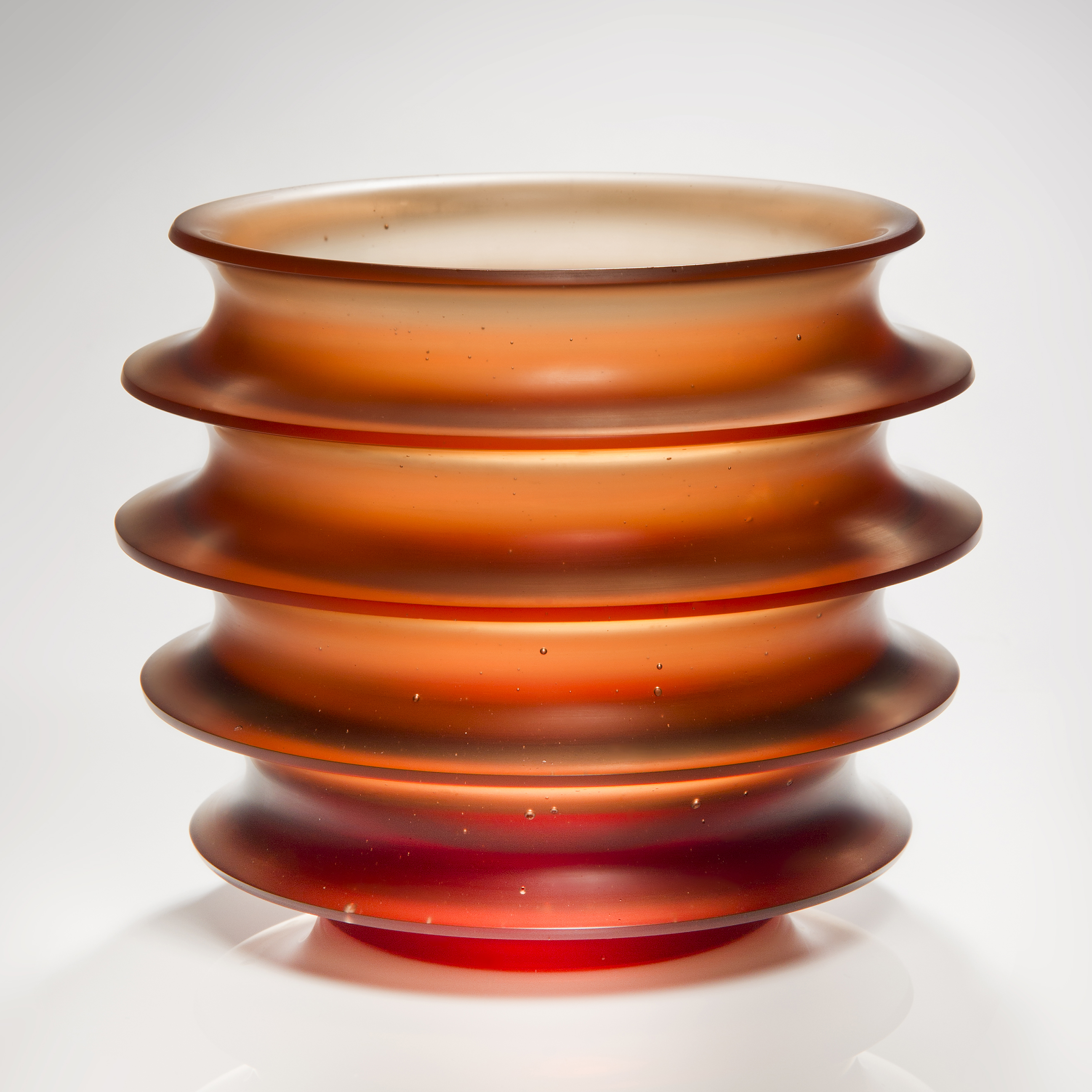orange minimalist glass sculpture with five protruding rings
