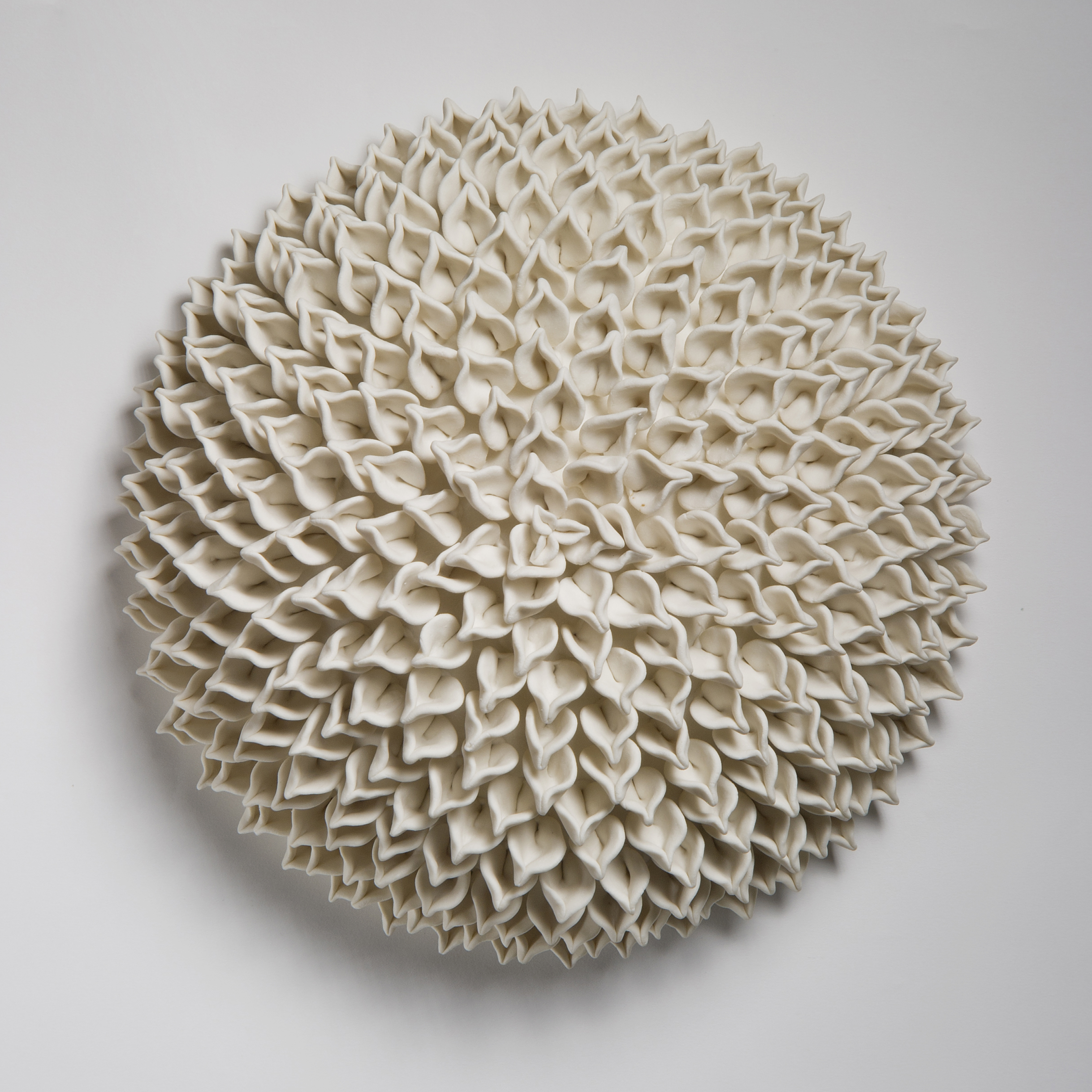 wall hanging geometric looking ceramic artwork of flowers in white