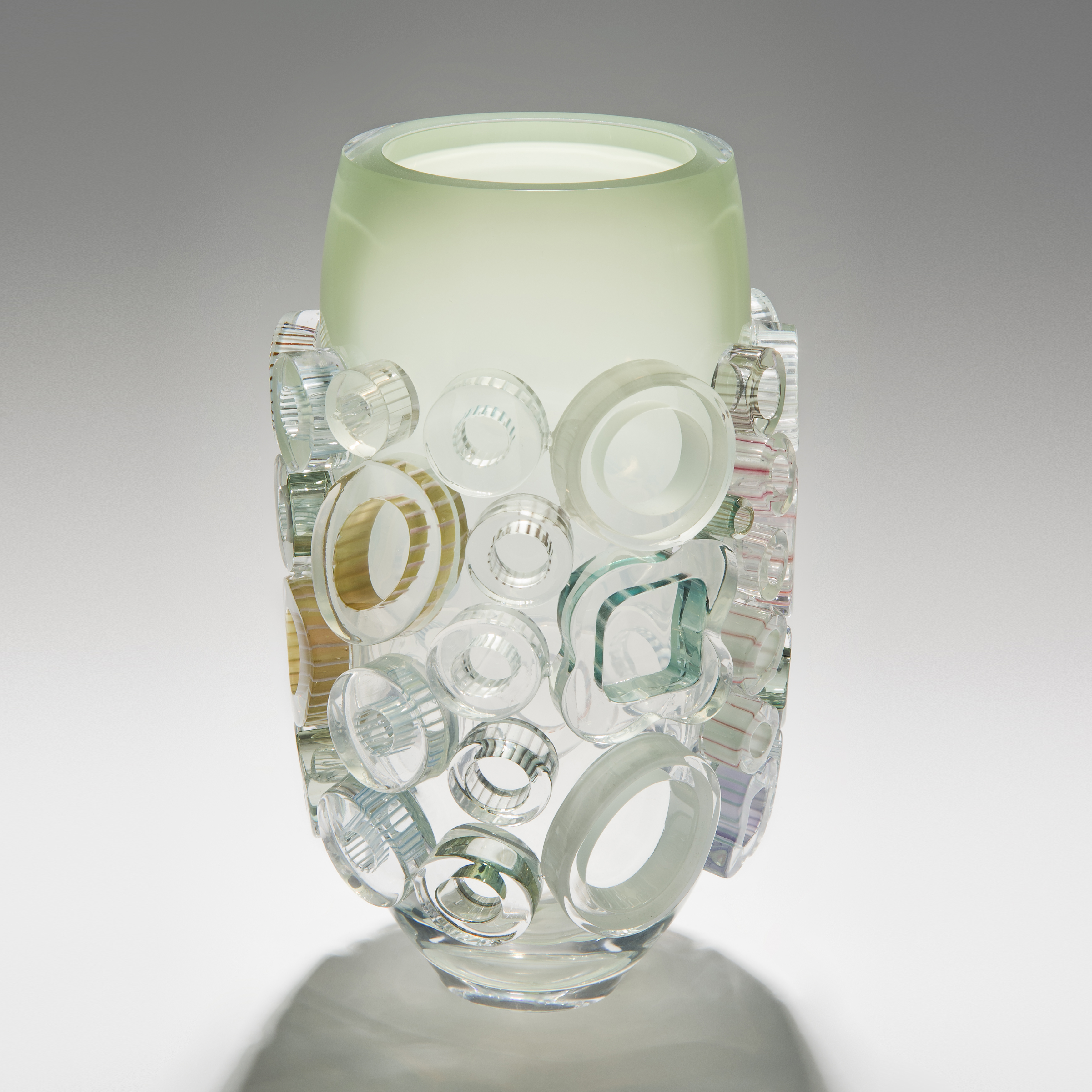 clear and green handblown glass vase sculpture with light coloured circular additions to the exterior