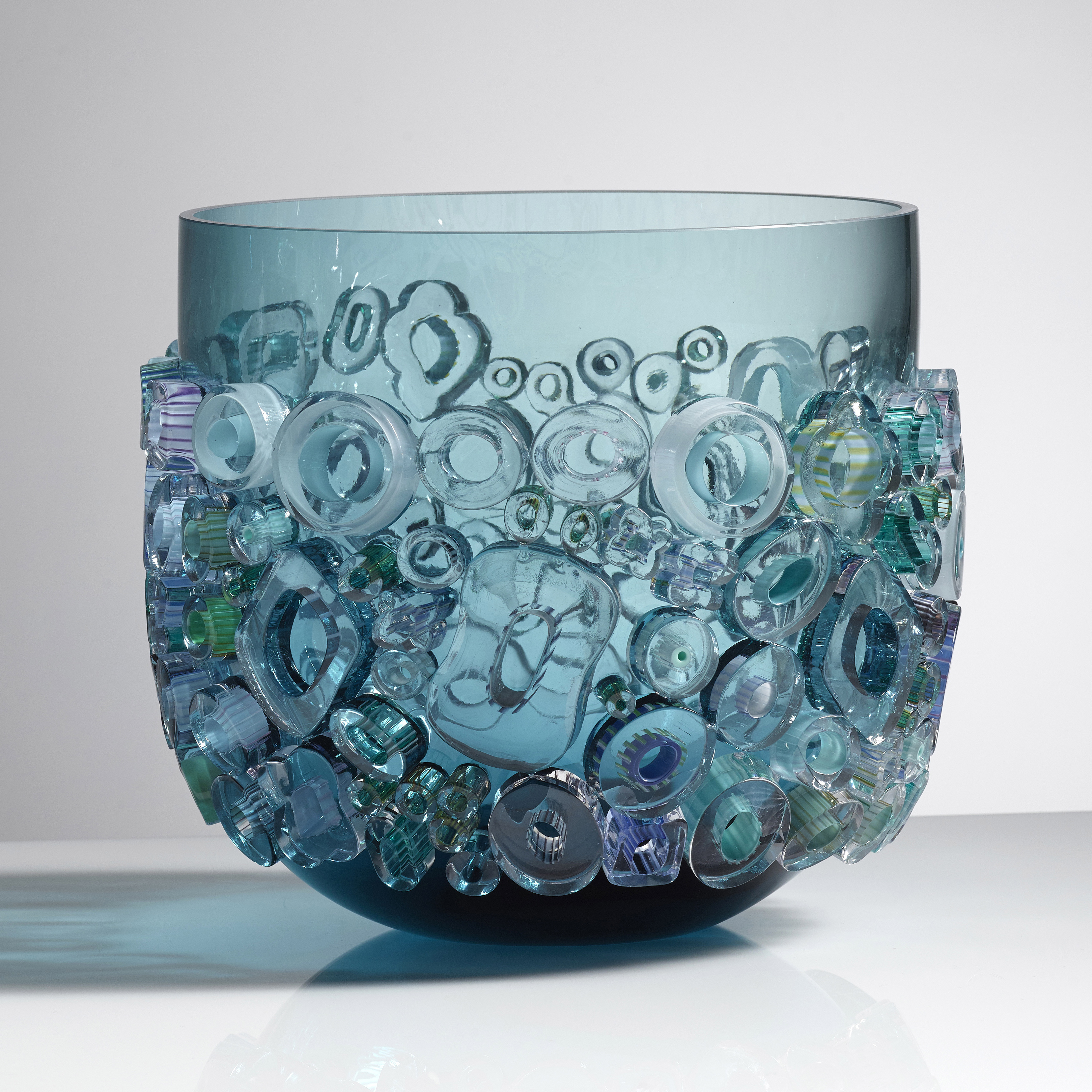 aqua blue coloured open glass vessel sculpture with busy external adornment