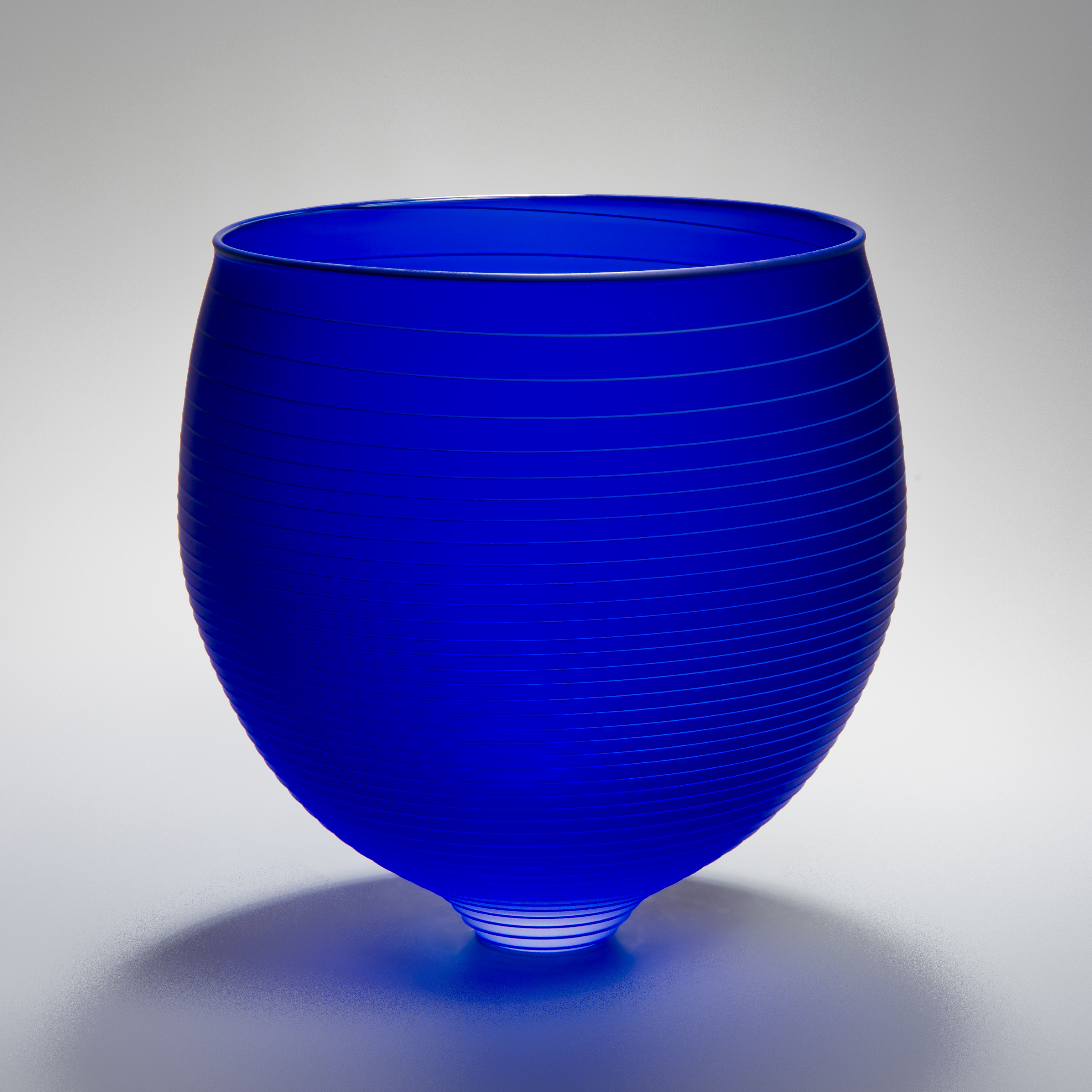 decorative glass bowl sculpture in deep blue with horizontal lines patterned throughout