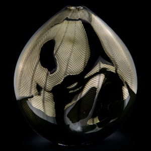 handblown minimalist glass teardrop shaped sculpted vessel in dark gold and black with wave checked external pattern