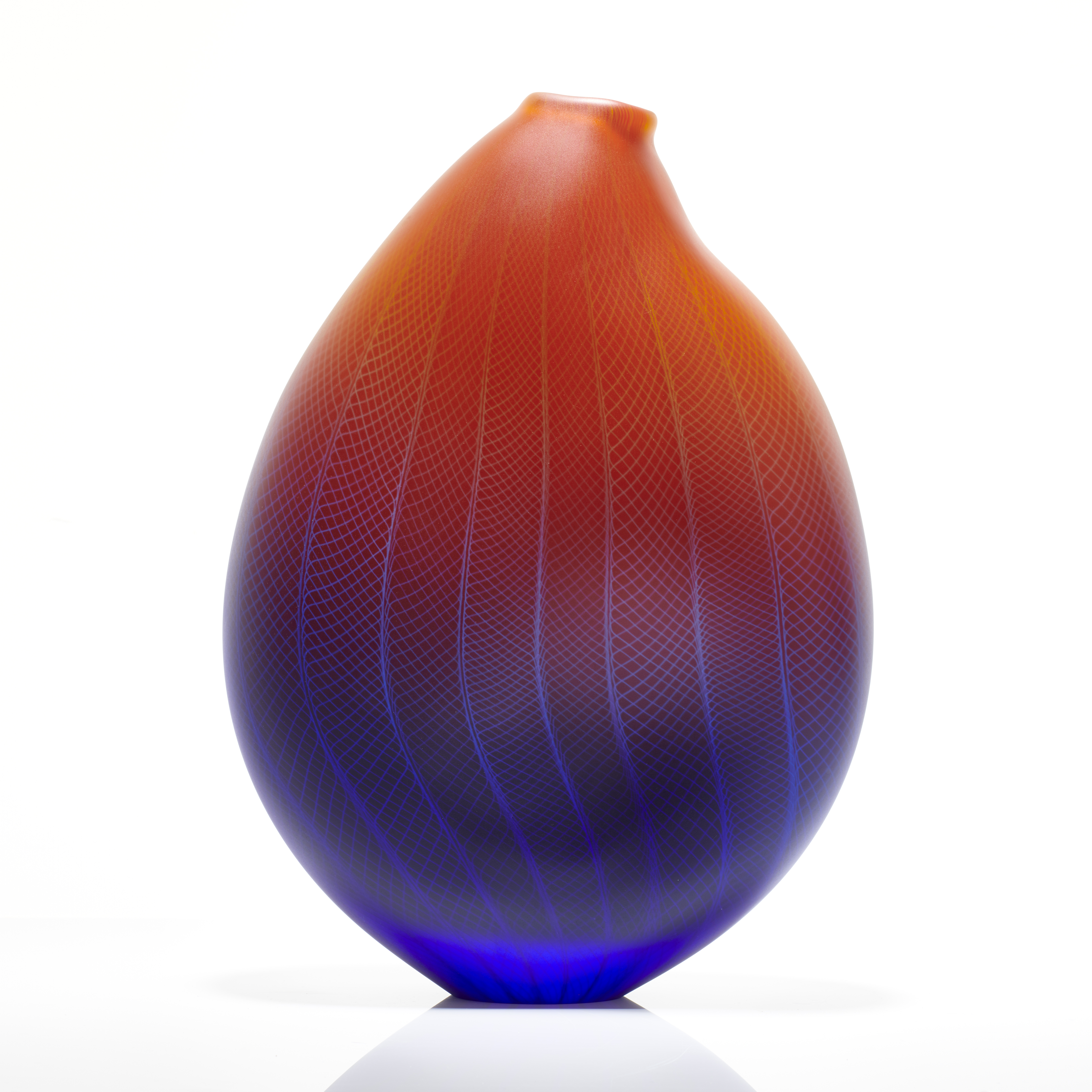 sculpted glass vessel in blue red and orange with small open top and lined and checked external engraved pattern