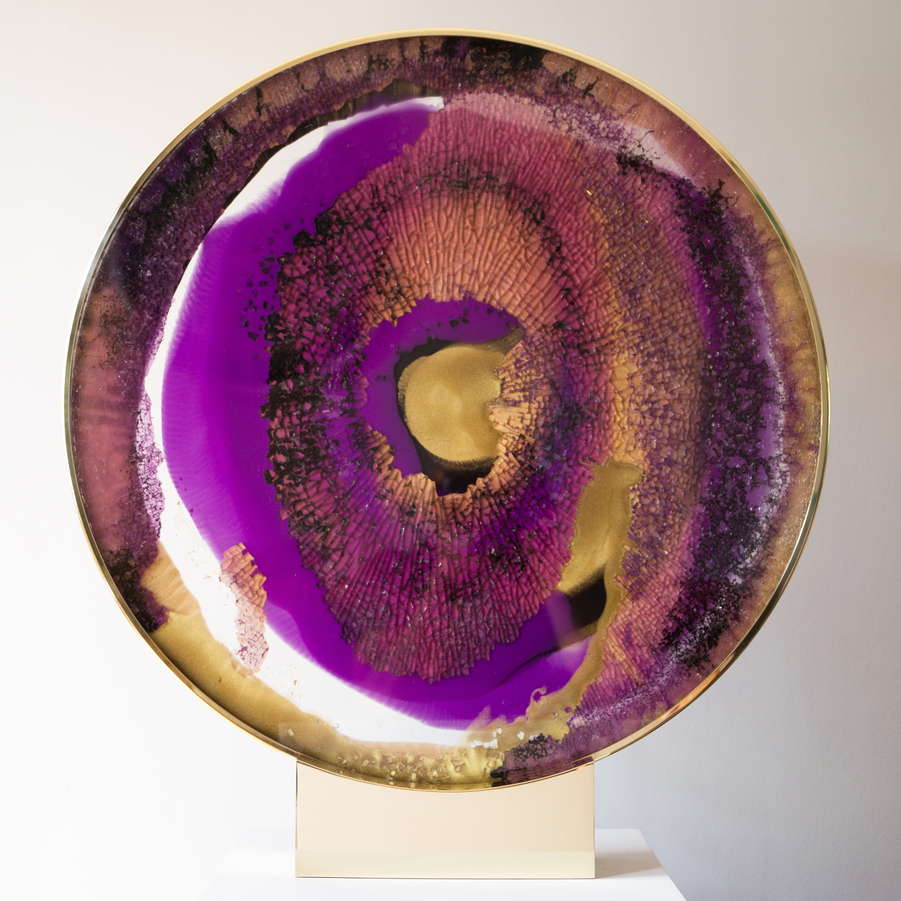 round glass art sculpture in deep purple yellow and brown resembling pattern of an eyeball