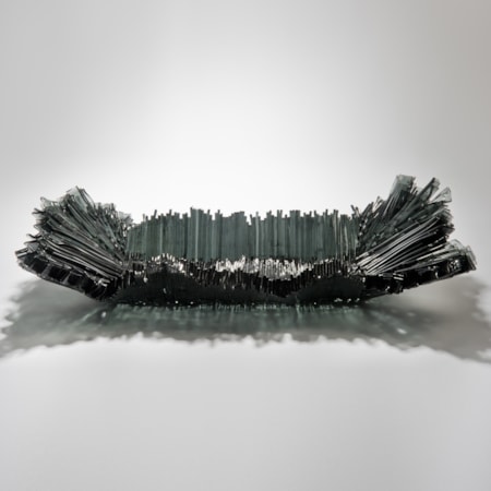 modern art-glass sculpture with hundreds of long thin dark grey shards arranged around edge to form bowl