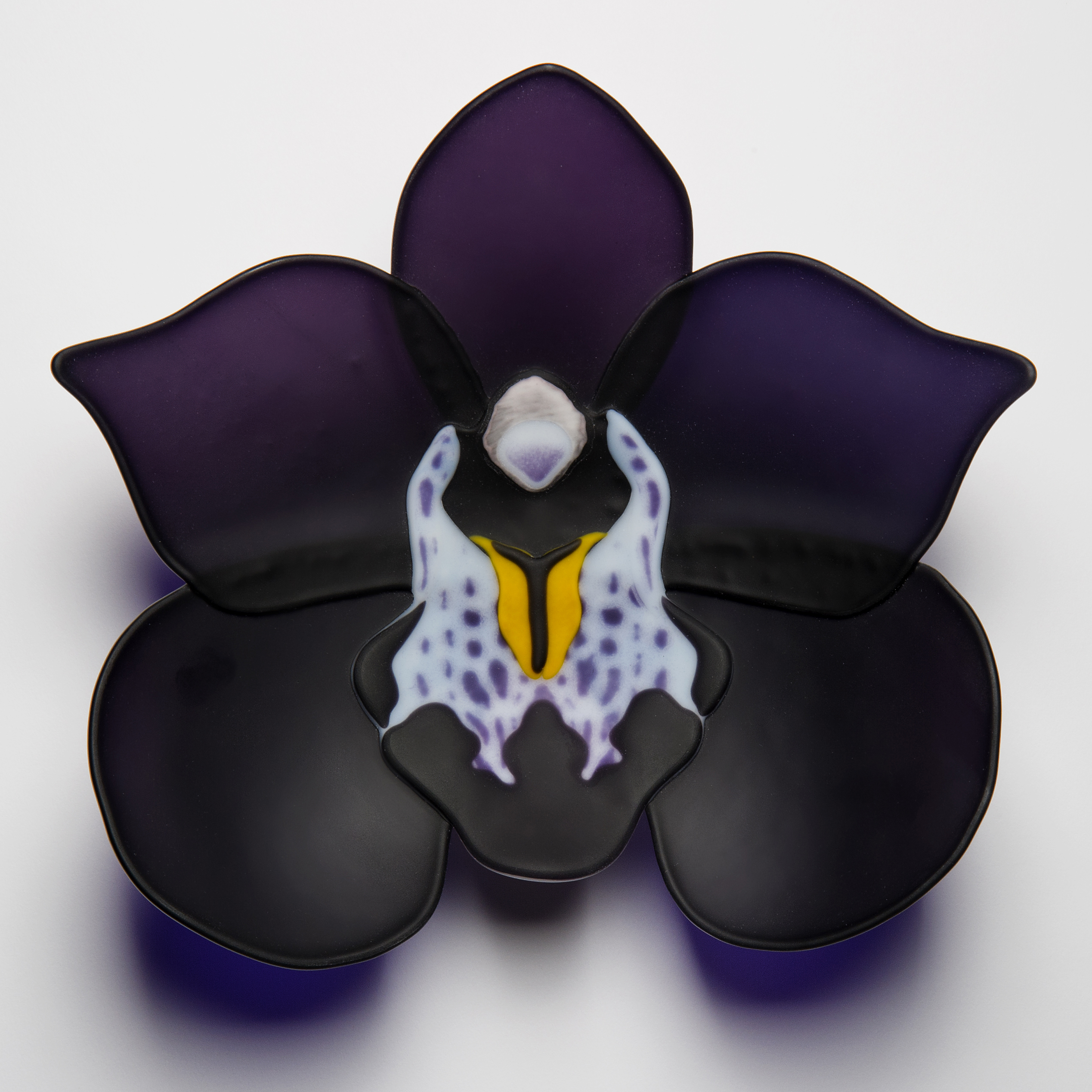 sculpted glass artwork of a black and dark purple flower with lighter detail in centre