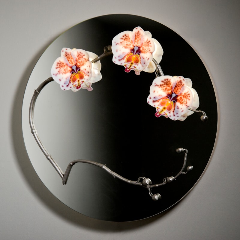 round black glass mirror with three sculpted glass orchids