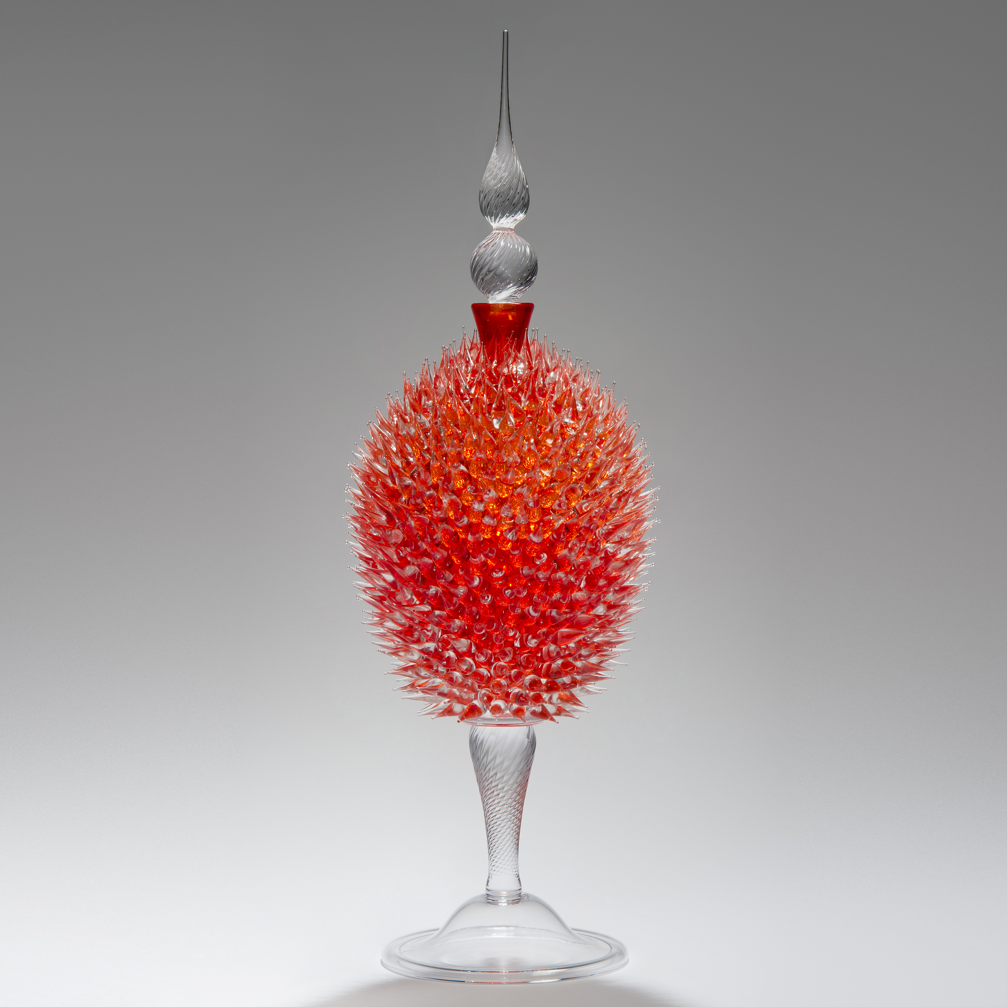 glass sculpture of spiked orange ball in the centre of clear glass base and top