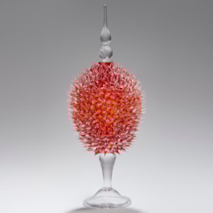 glass sculpture of spiked cherry red ball in the centre of clear glass base and top