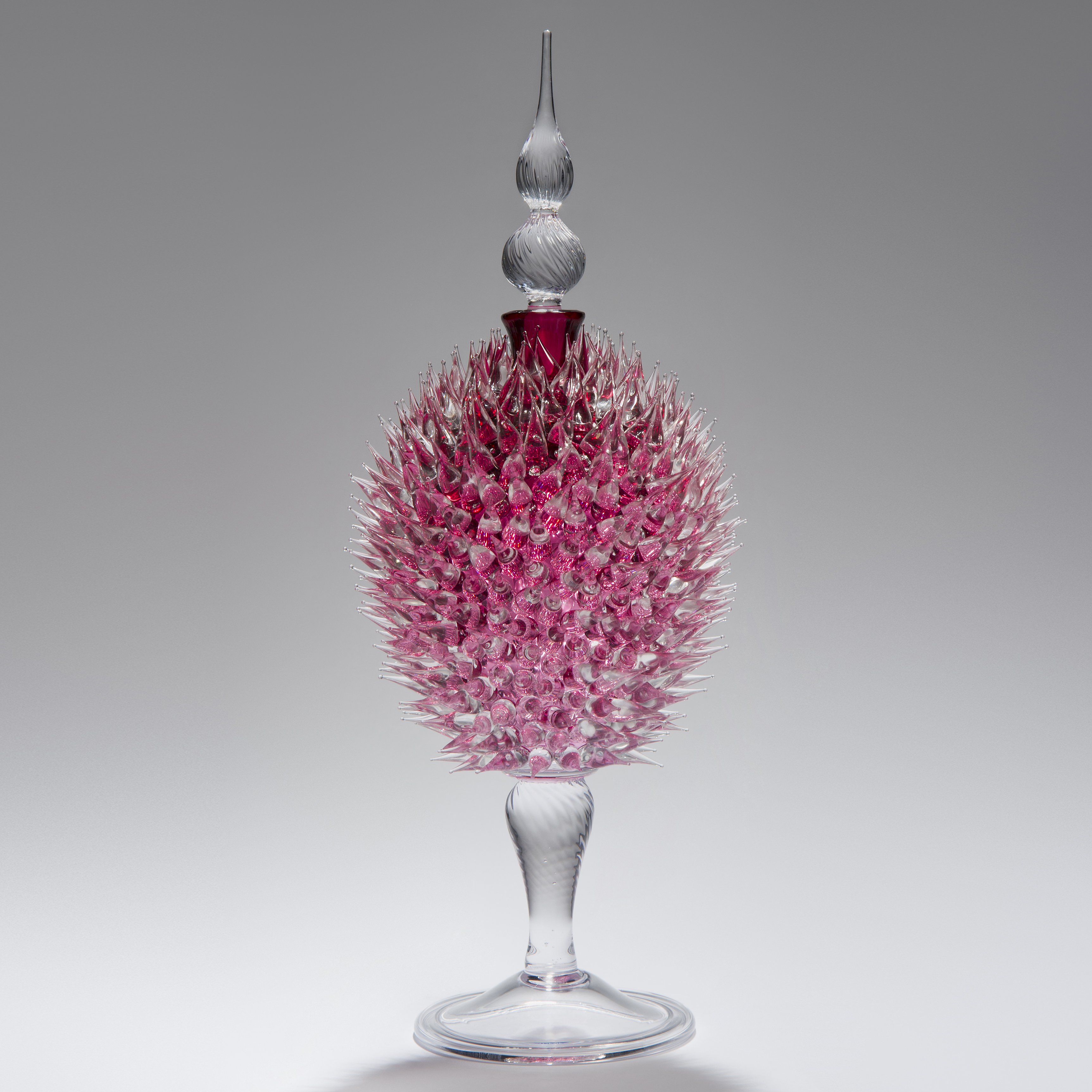glass sculpture of spiked ruby red ball in the centre of clear glass base and top