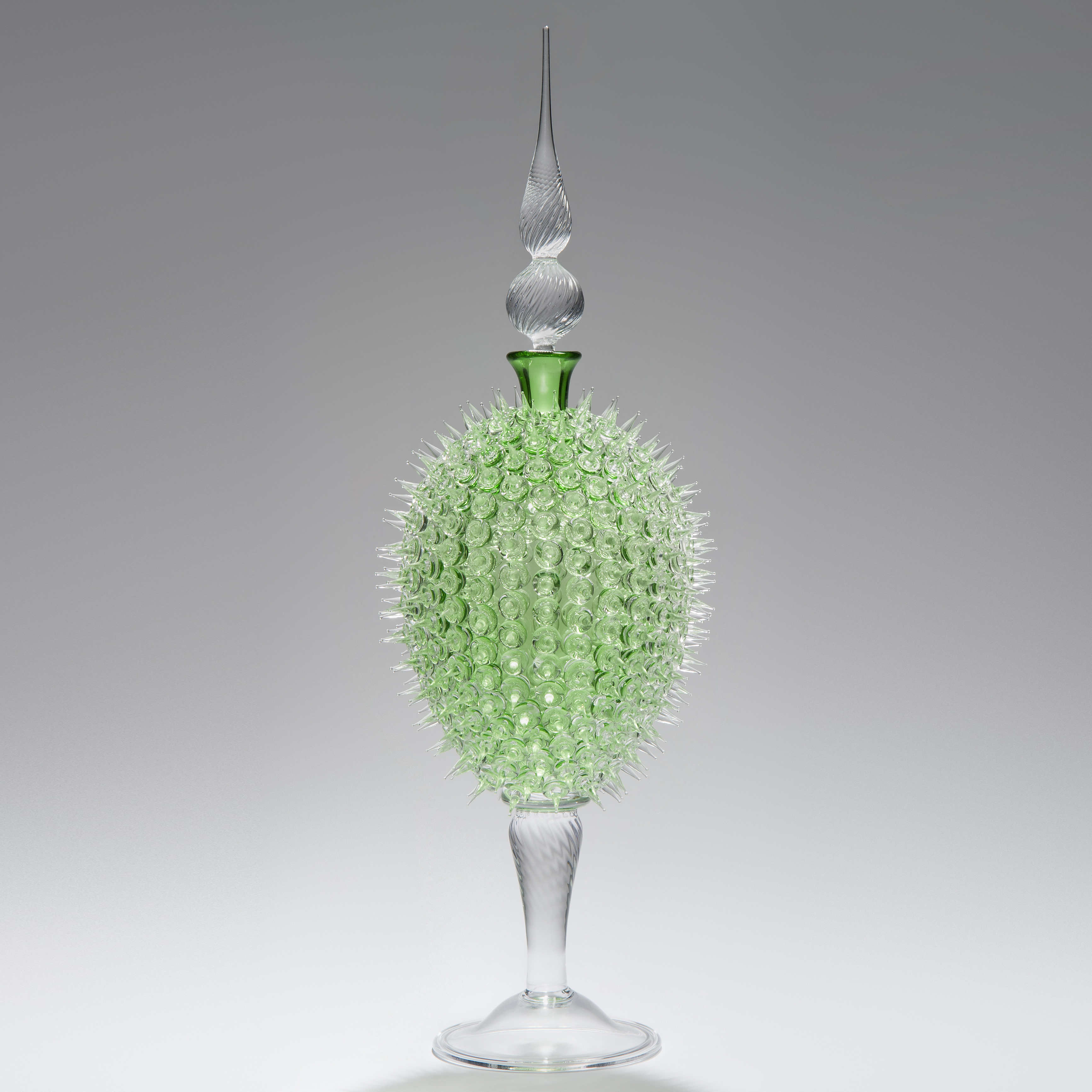 glass sculpture of spiked neon green ball in the centre of clear glass base and top