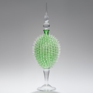 glass sculpture of spiked neon green ball in the centre of clear glass base and top