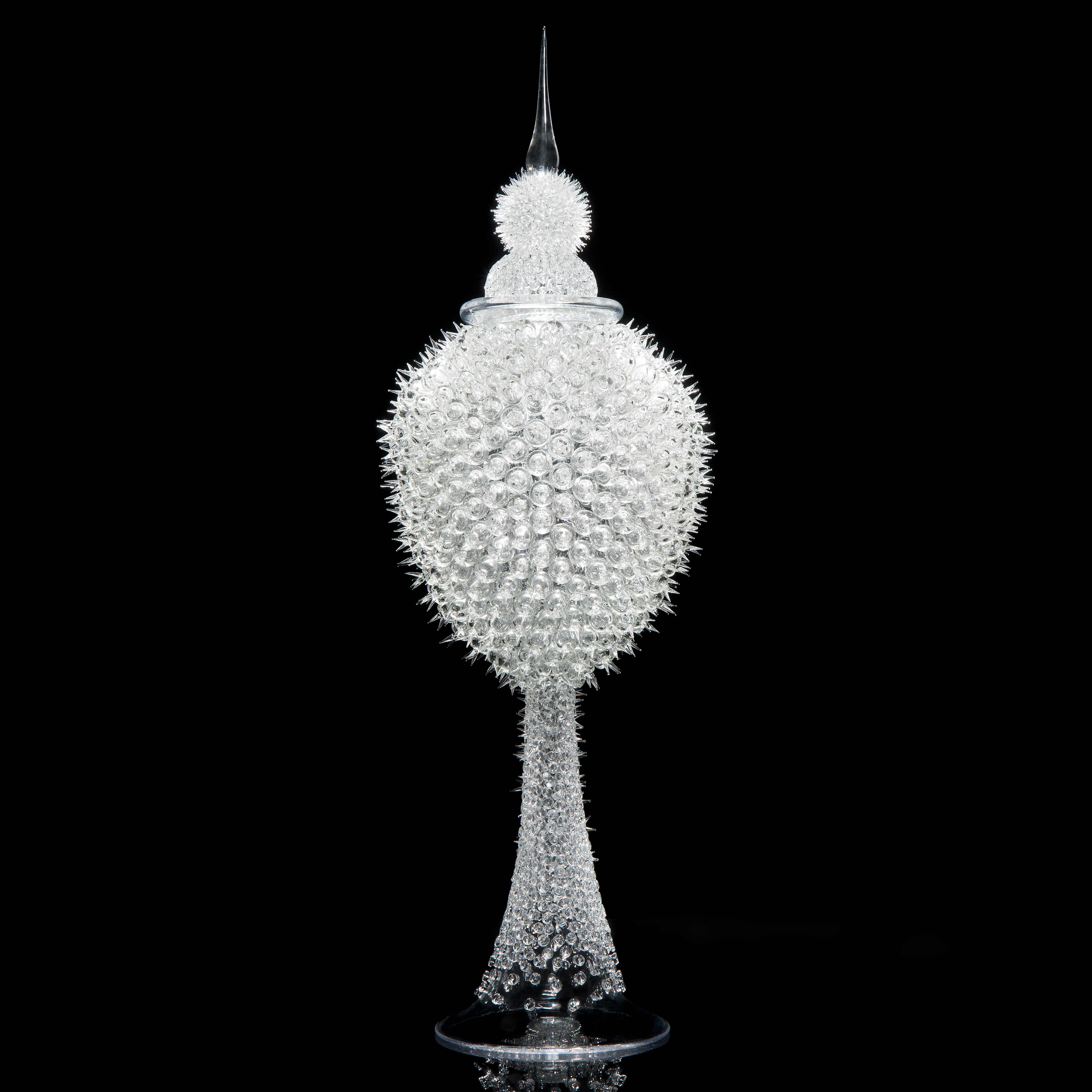 tall white glass sculpture of rounded prickly blobs on long cone with pointed top