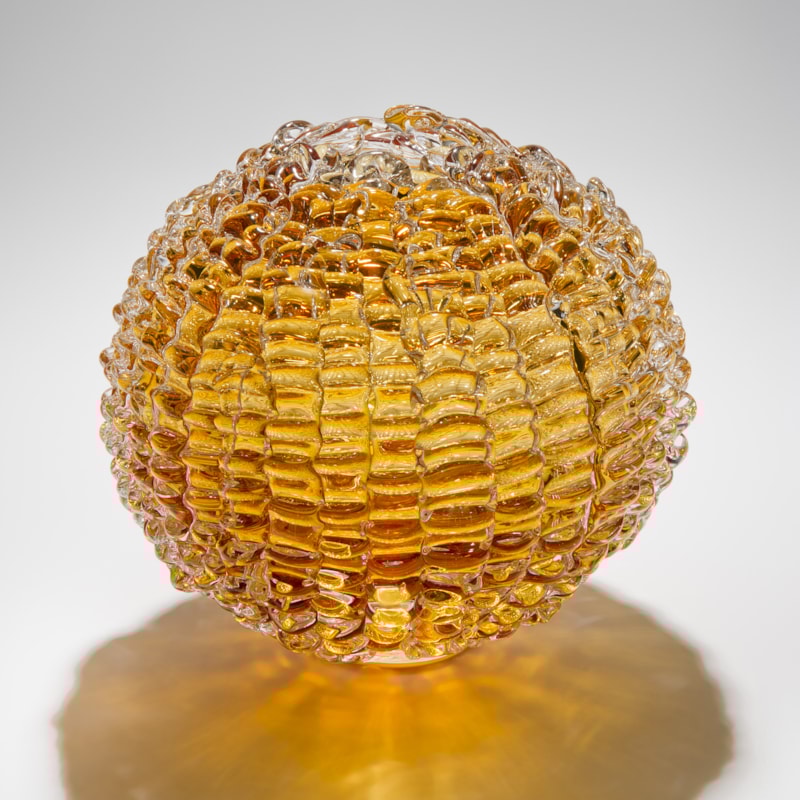 sphere shaped blown glass sculpture in amber made from stacked small shards