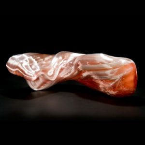 stretched and bent glass formation of abstract sculpture in pink and coral