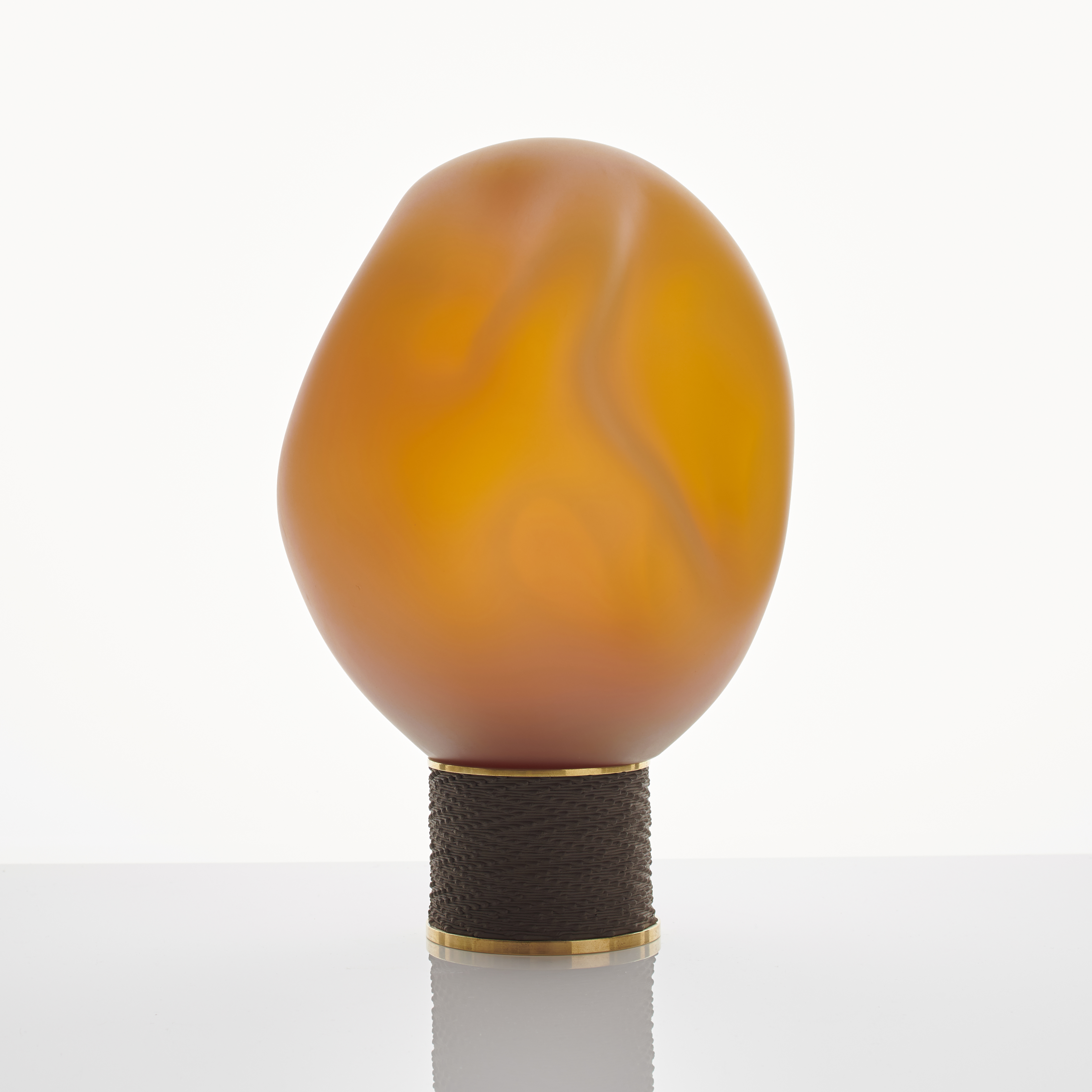 orange modern glass art sculpture of blob shape from blown glass resting on bronze base