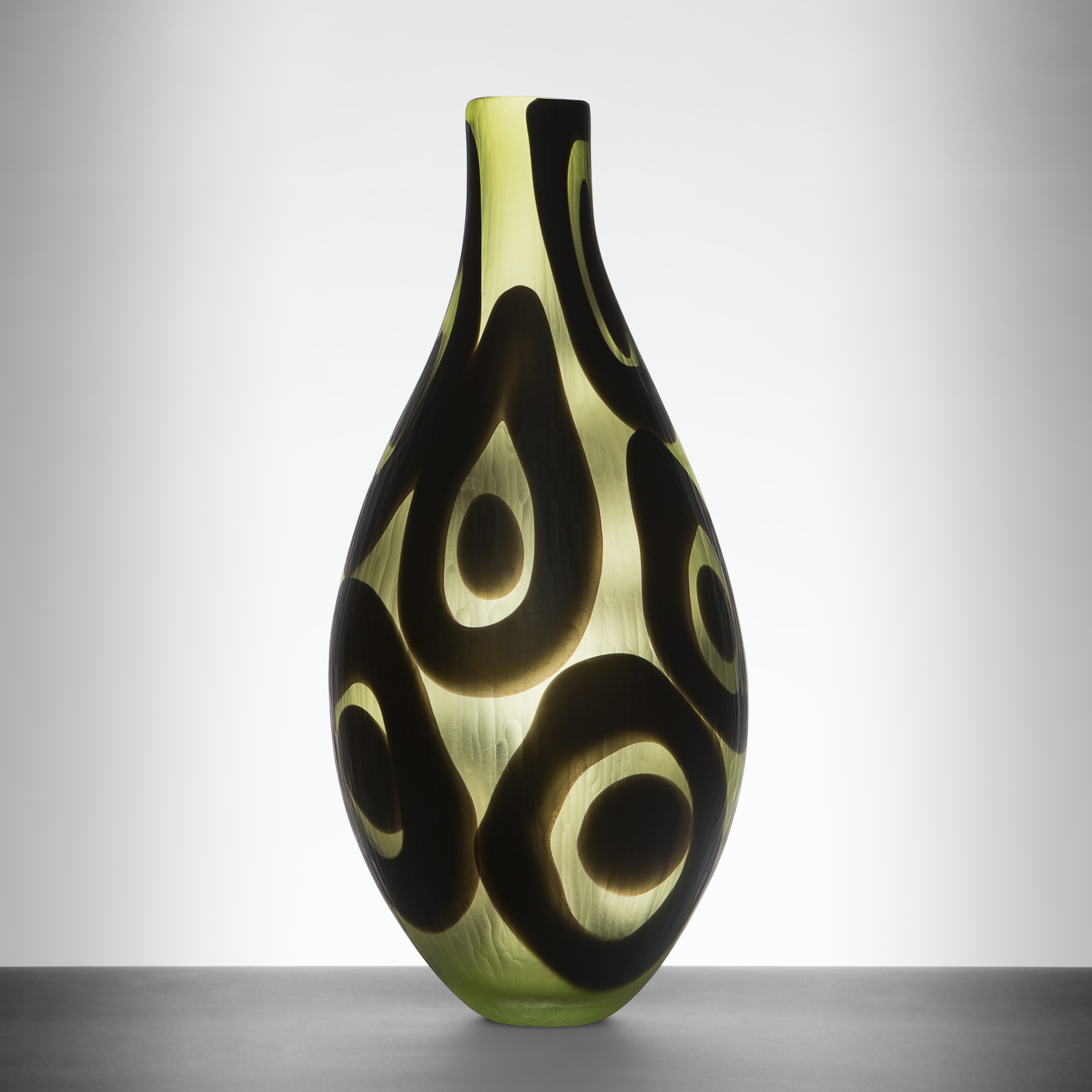 modern glass art sculpted vessel with thin neck in light green with black circle pattern
