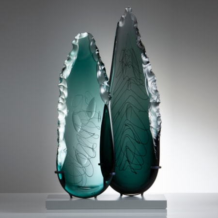 two leaf-shaped glass art sculptures in aqua and jade on clear rectangular base