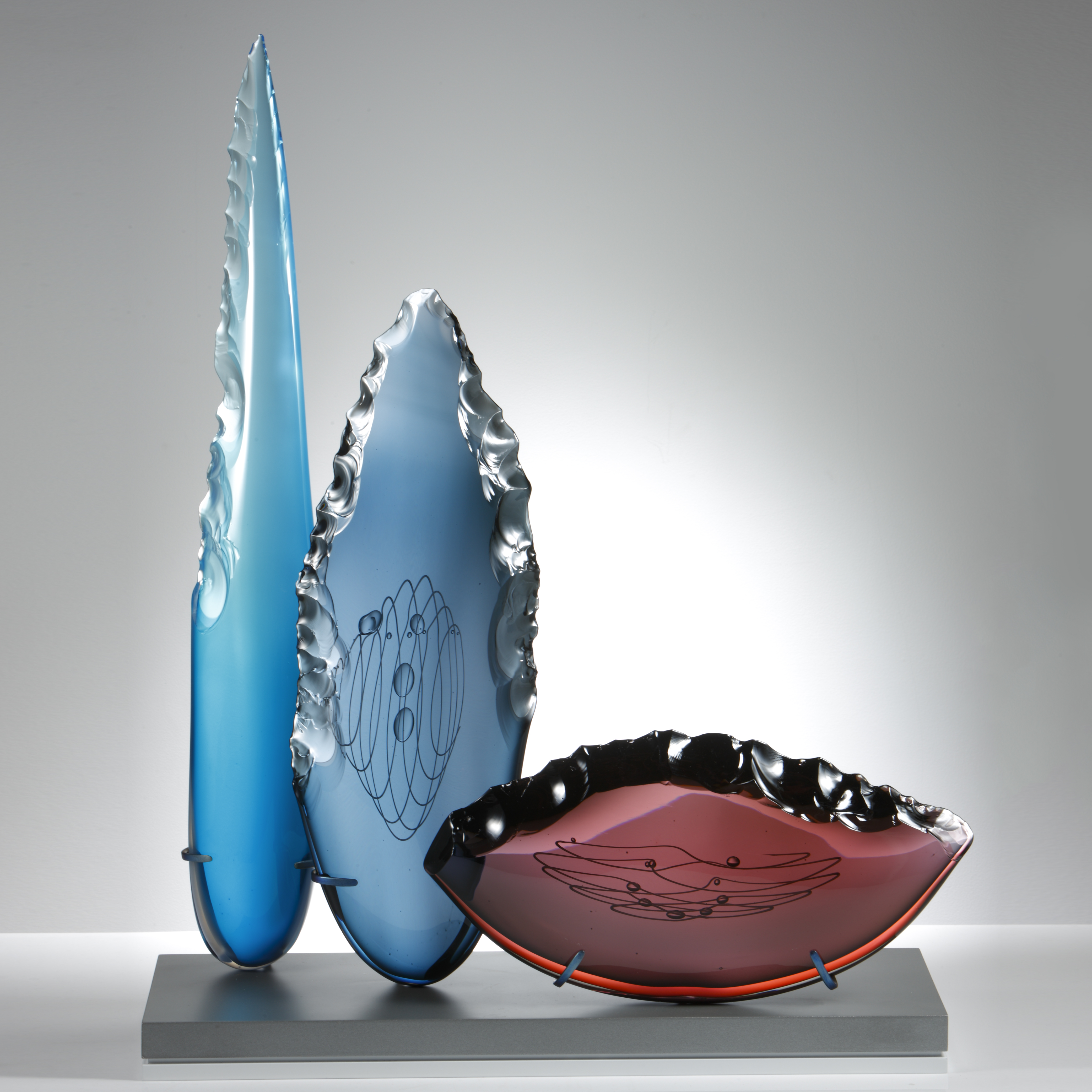 blue steel and plum glass cloves in different heights and shapes on grey glass base