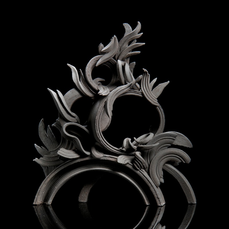 black stoneware sculpture in classical style with arcs and flares