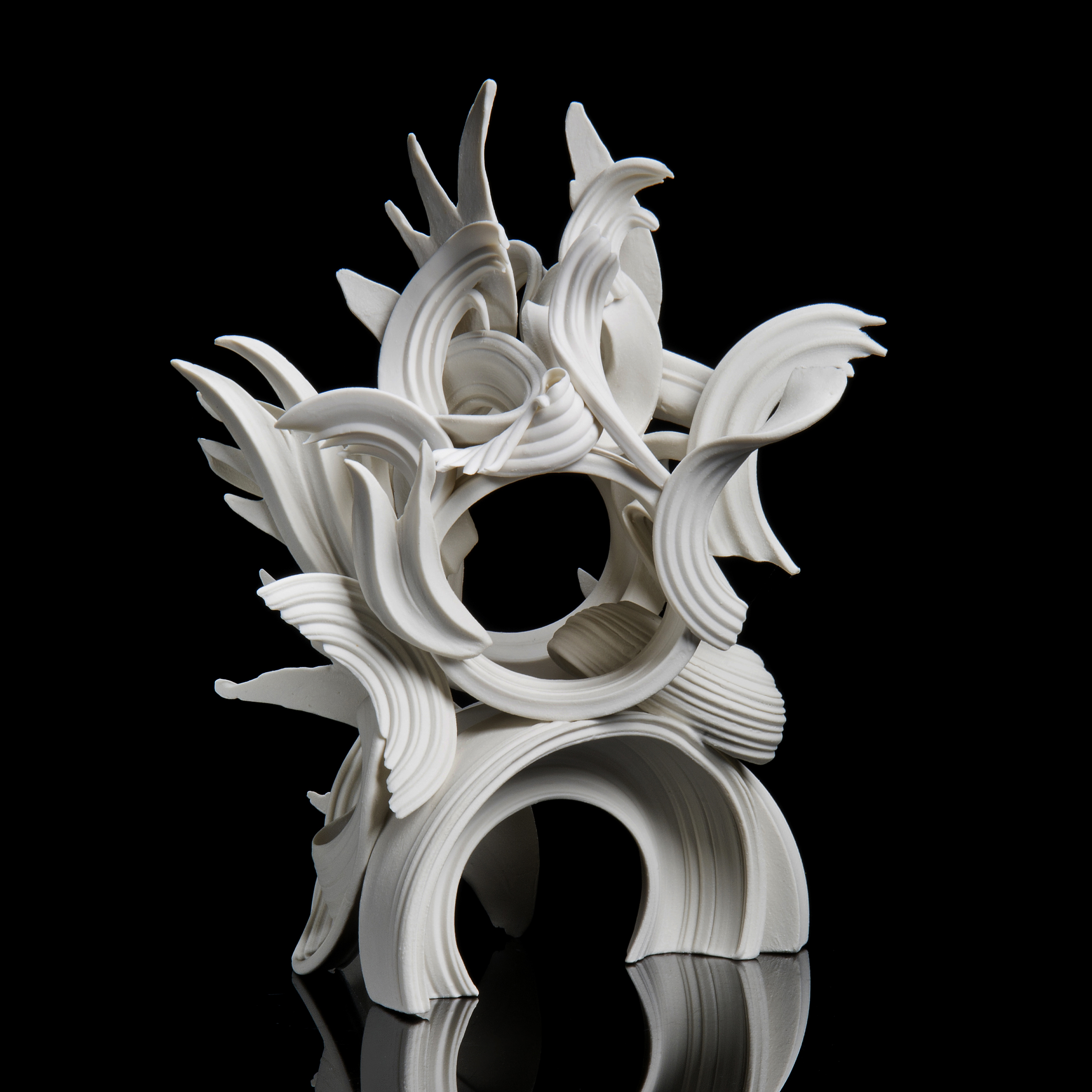 white porcelain sculpture in classical style of arcs and flares intertwined