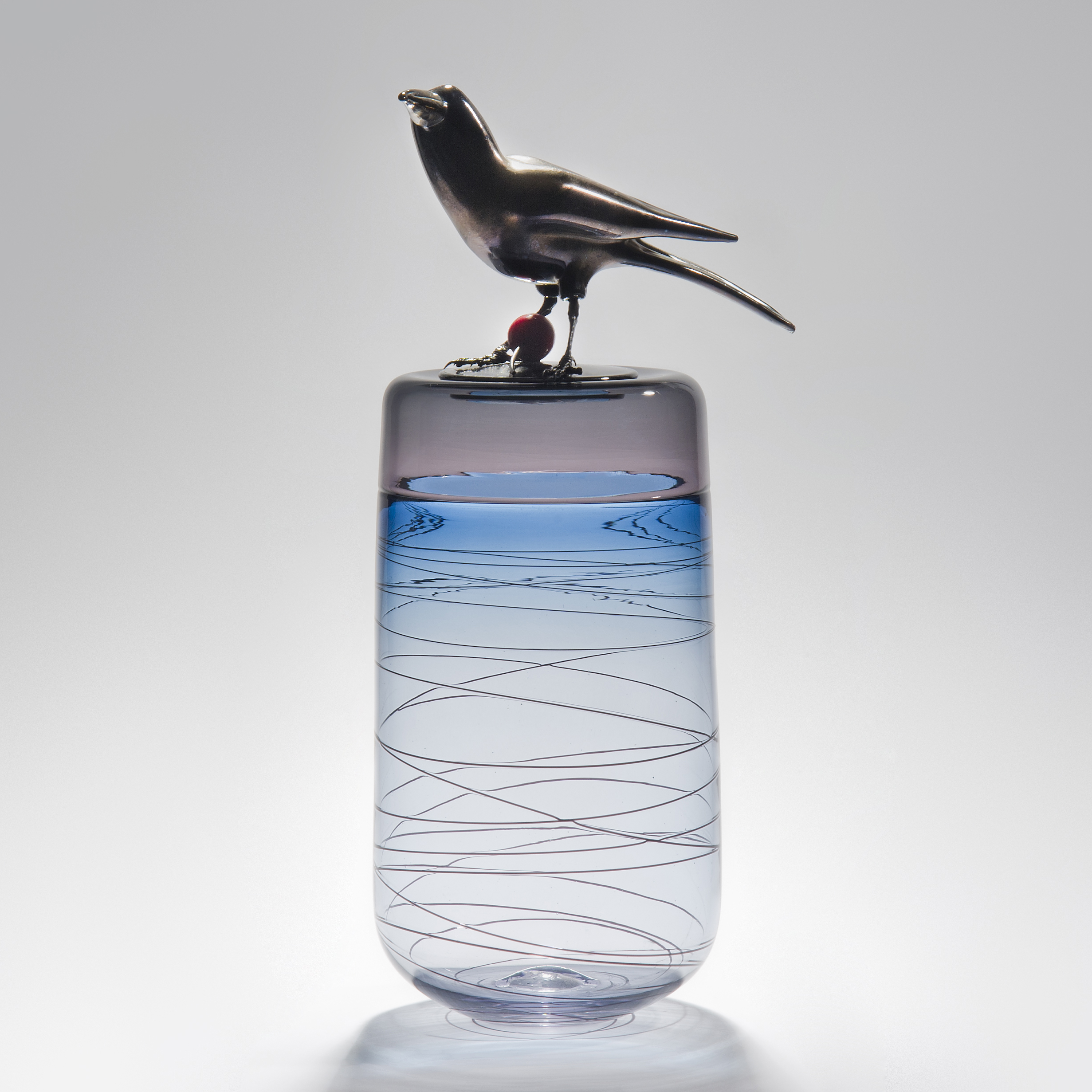 sculpted glass case in white, light blue and pink with helter skelter line pattern on exterior and stainless steel crow on top with red cherry