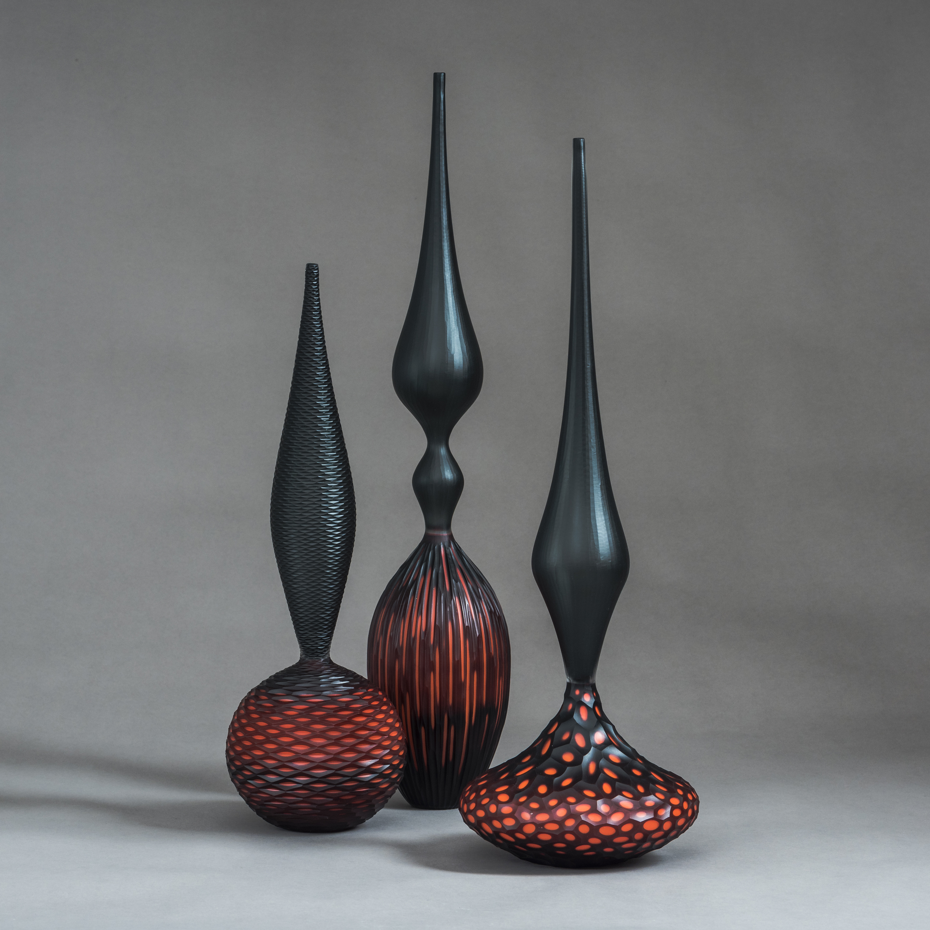 red and black contemporary geometrically patterned set of three sculptures made from handblown and cut glass