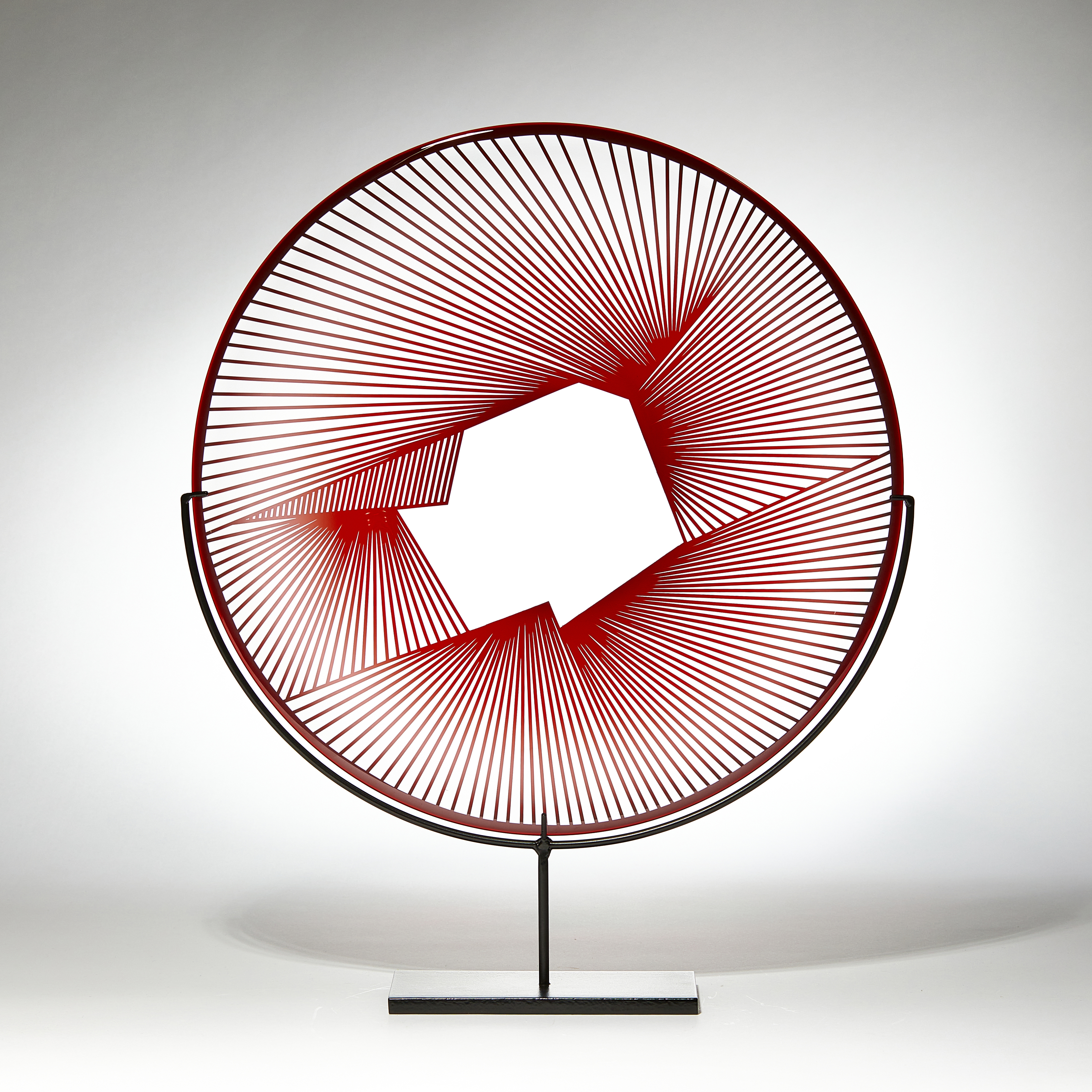 red and clear round sculptural glass plate made from handblown and cut glass with metal stand