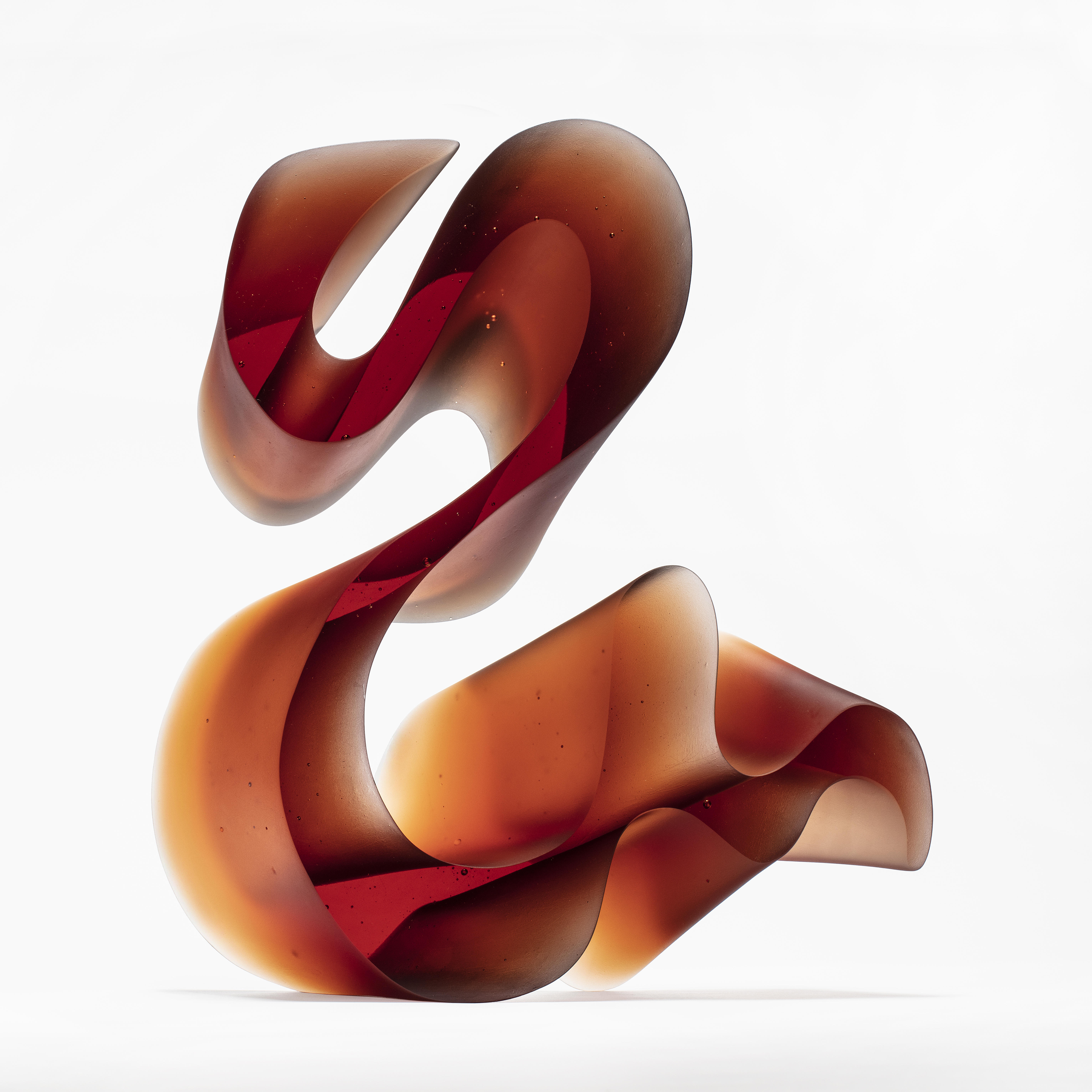 amber red fluid lined sculpture with dramatic sweeping curves made from cast glass