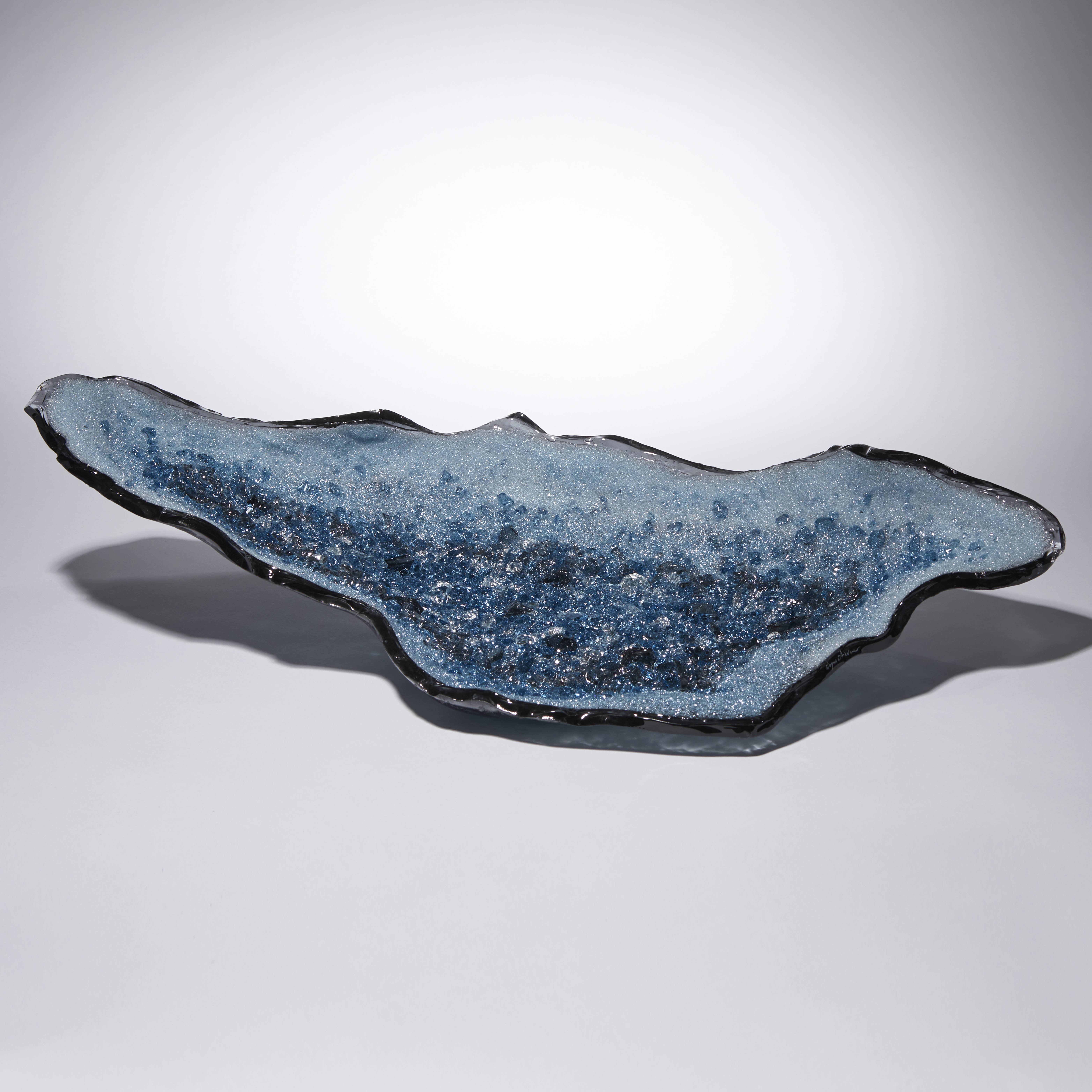 light and dark blue long organically shaped glass sculpture with a twinkling crystal covered interior