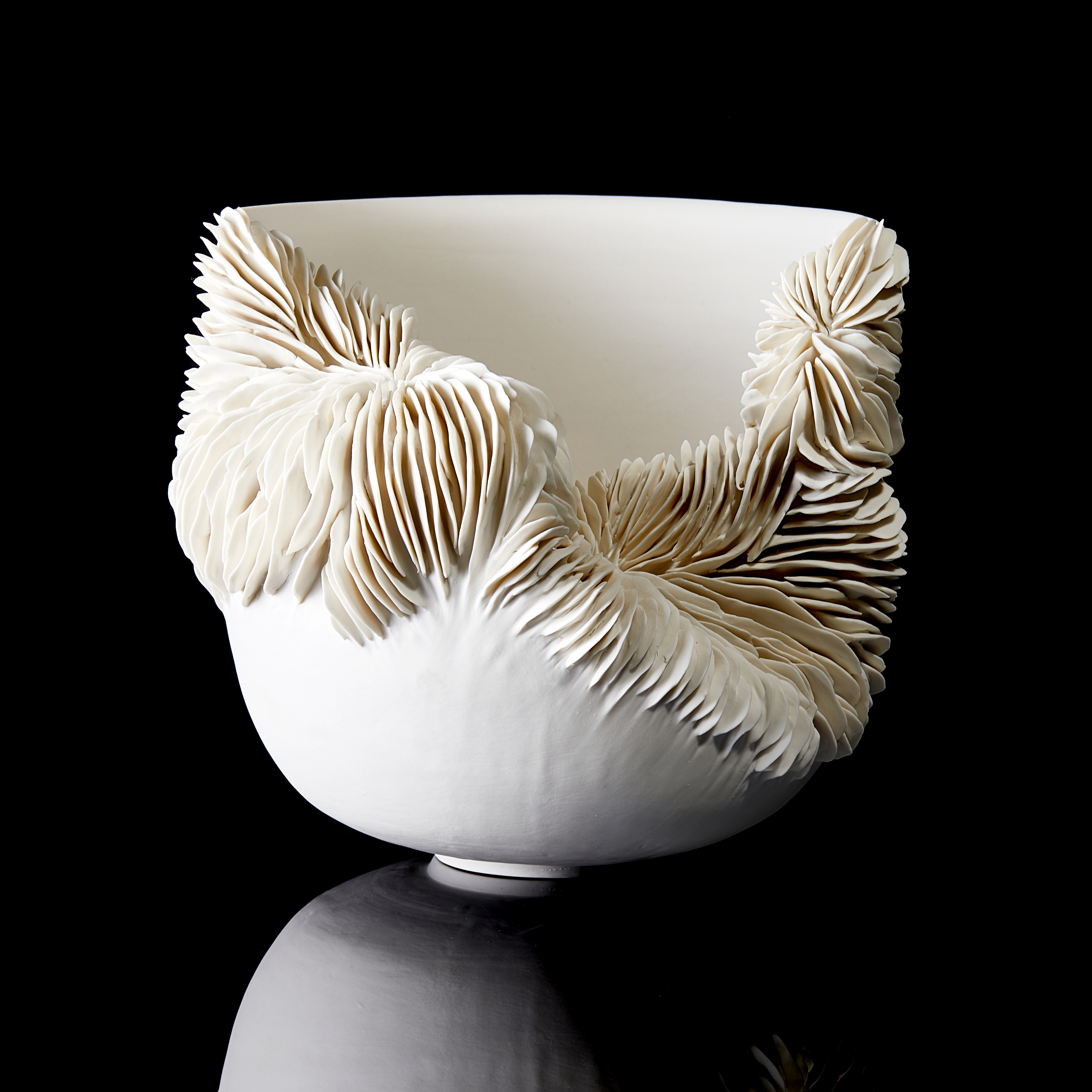 sculptural ceramic bowl with cut away side filled with ridged decoration handmade from porcelain