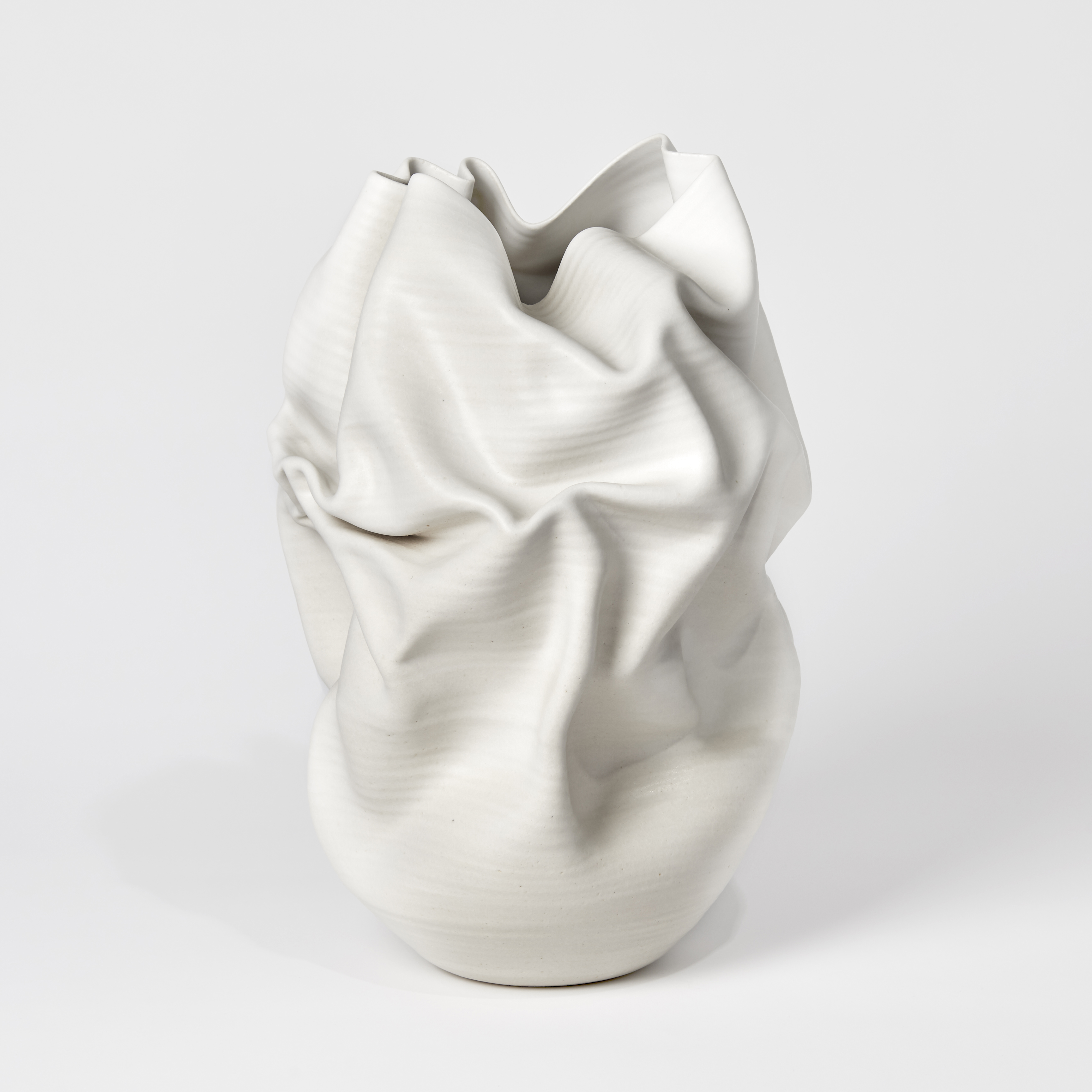 white crumpled and folded ceramic vessel with wobbly top edge handmade from clay