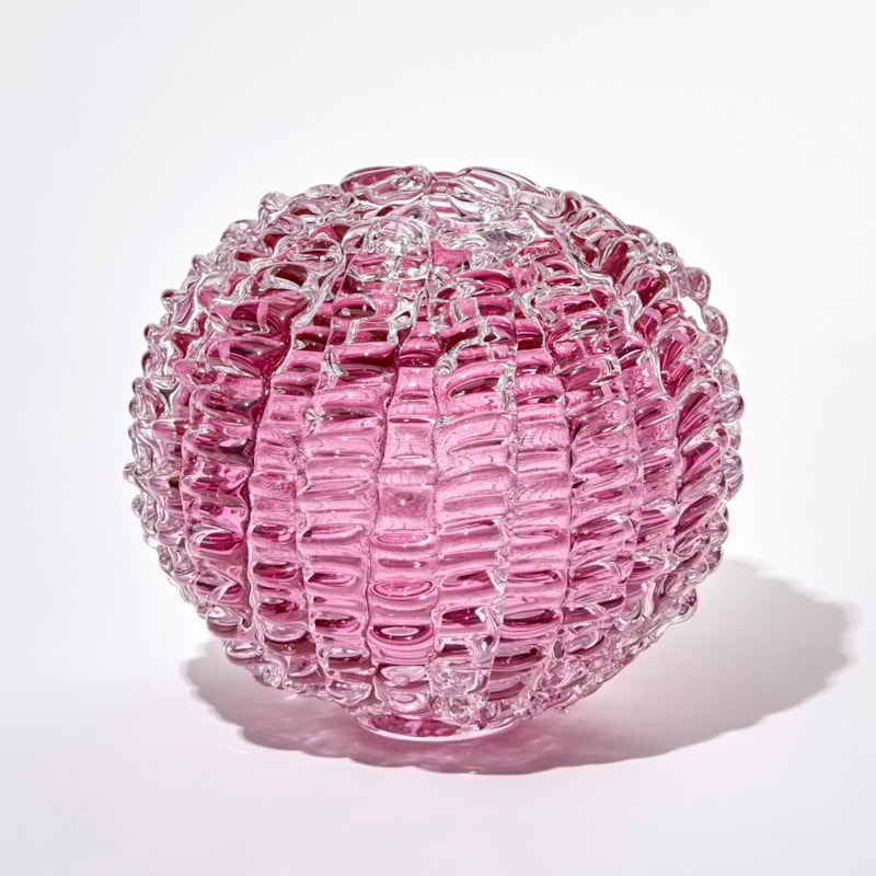 pink ridged globe shaped sculpture handmade and sculpted from glass with small top opening