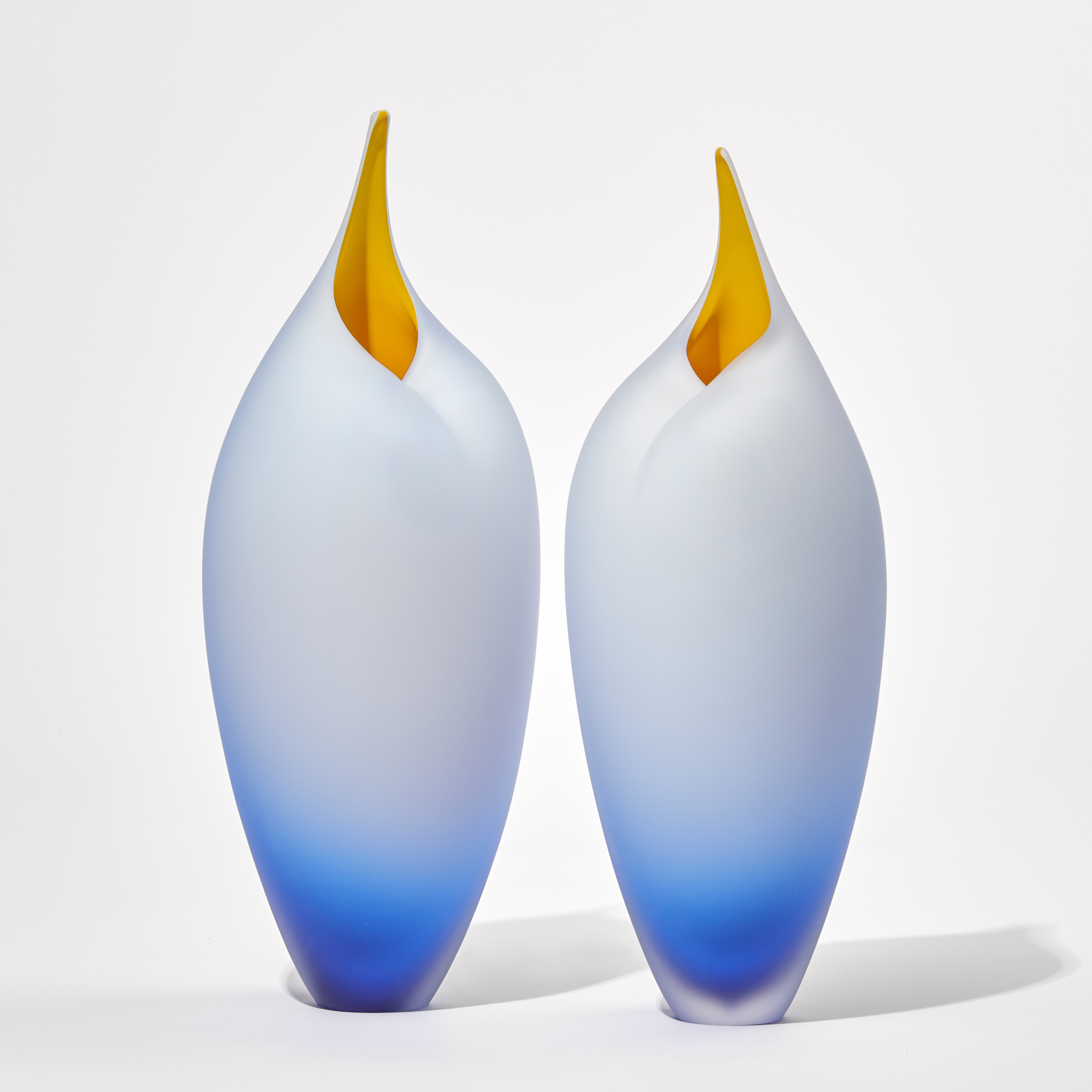 blue tall birds with rounded forms and open beaks and yellow mouths