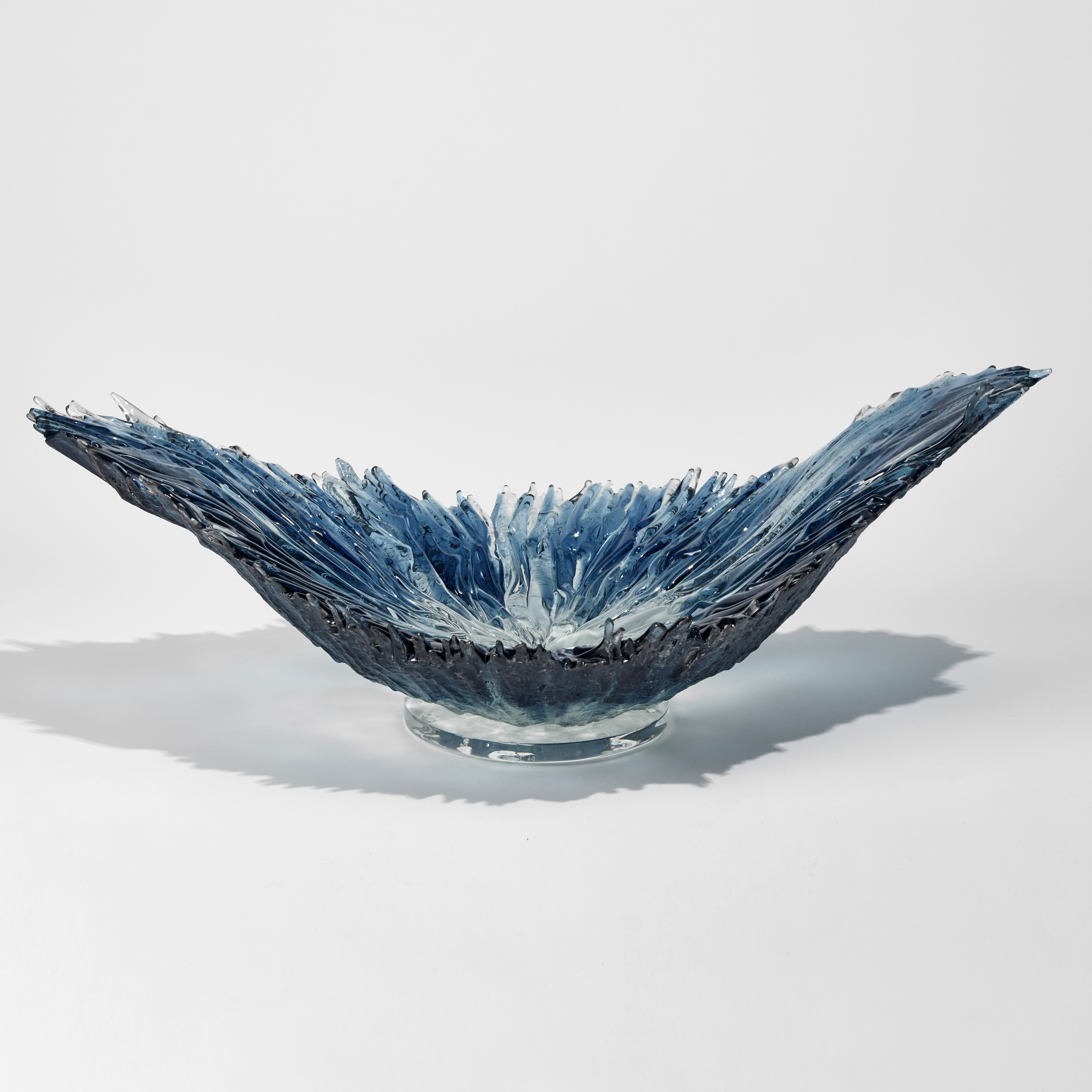 aqua and blue curved organic hand made glass bowl with the appearance of a wave
