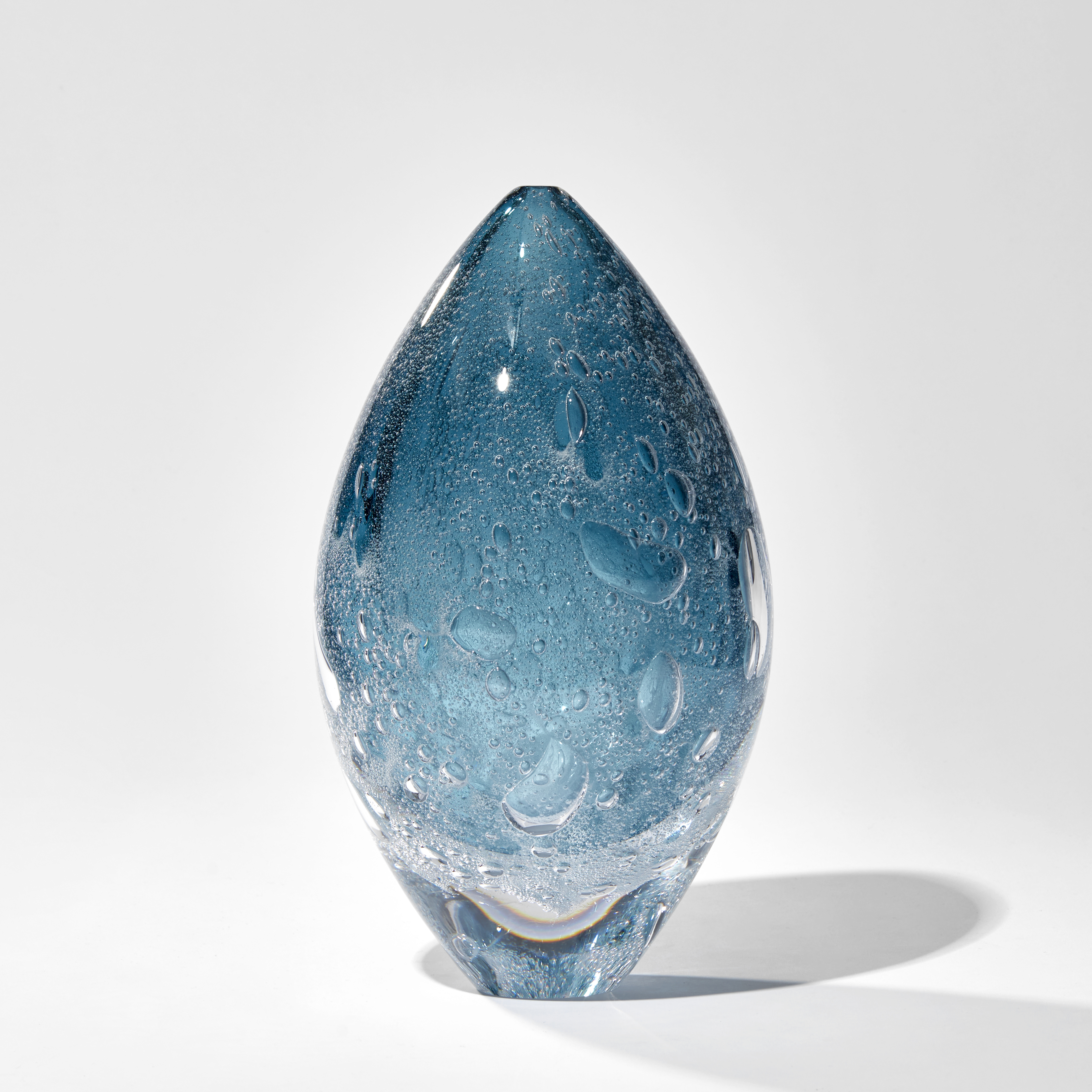 fading rich blue ovoid sculpture with internal bubbles hand made from glass