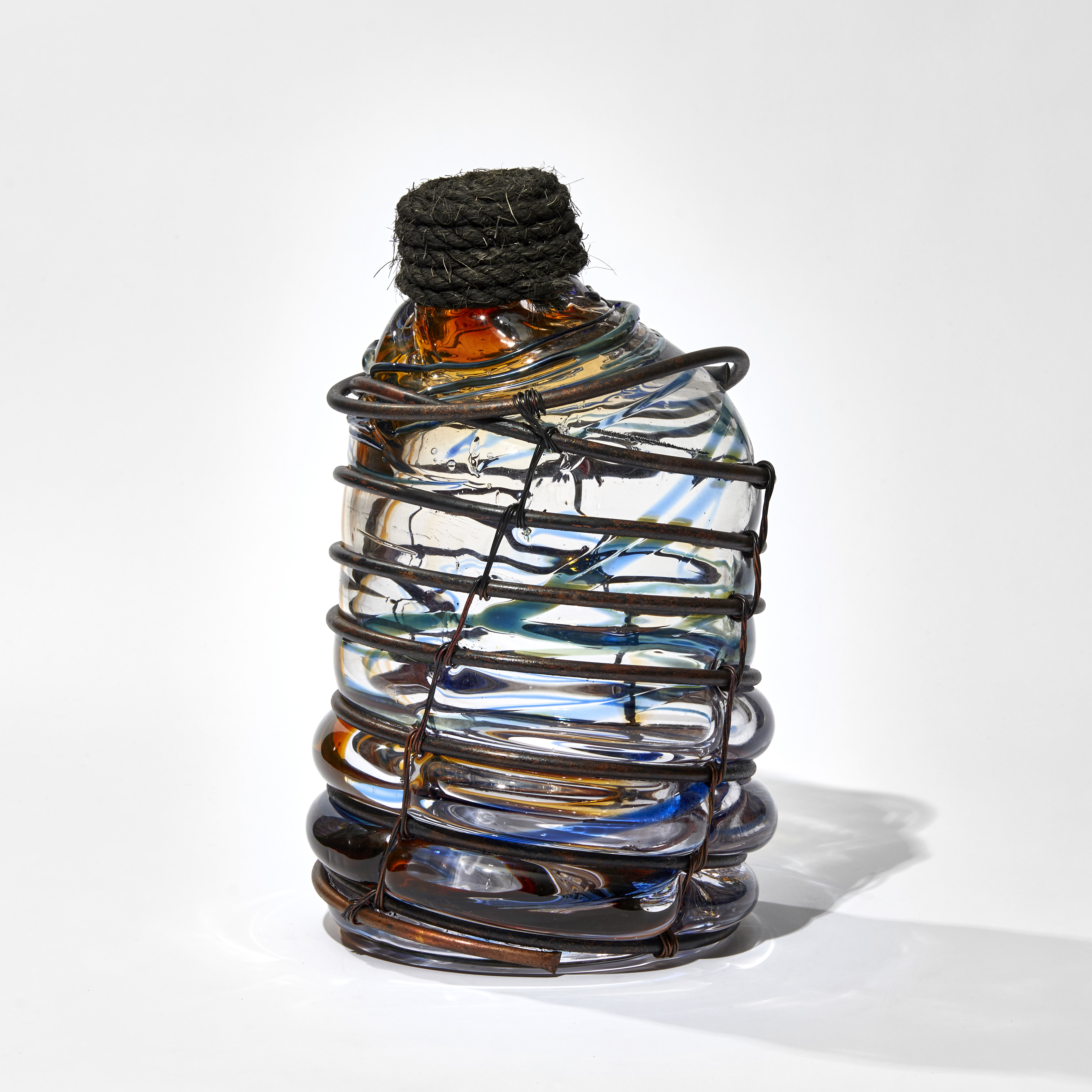 blue and amber transparent aged glass rum bottle formed in a copper cage with rope stopper hand made