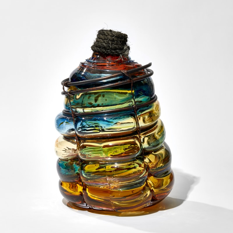 amber blue and red aged glass bottle with copper pipe binding and rope cork