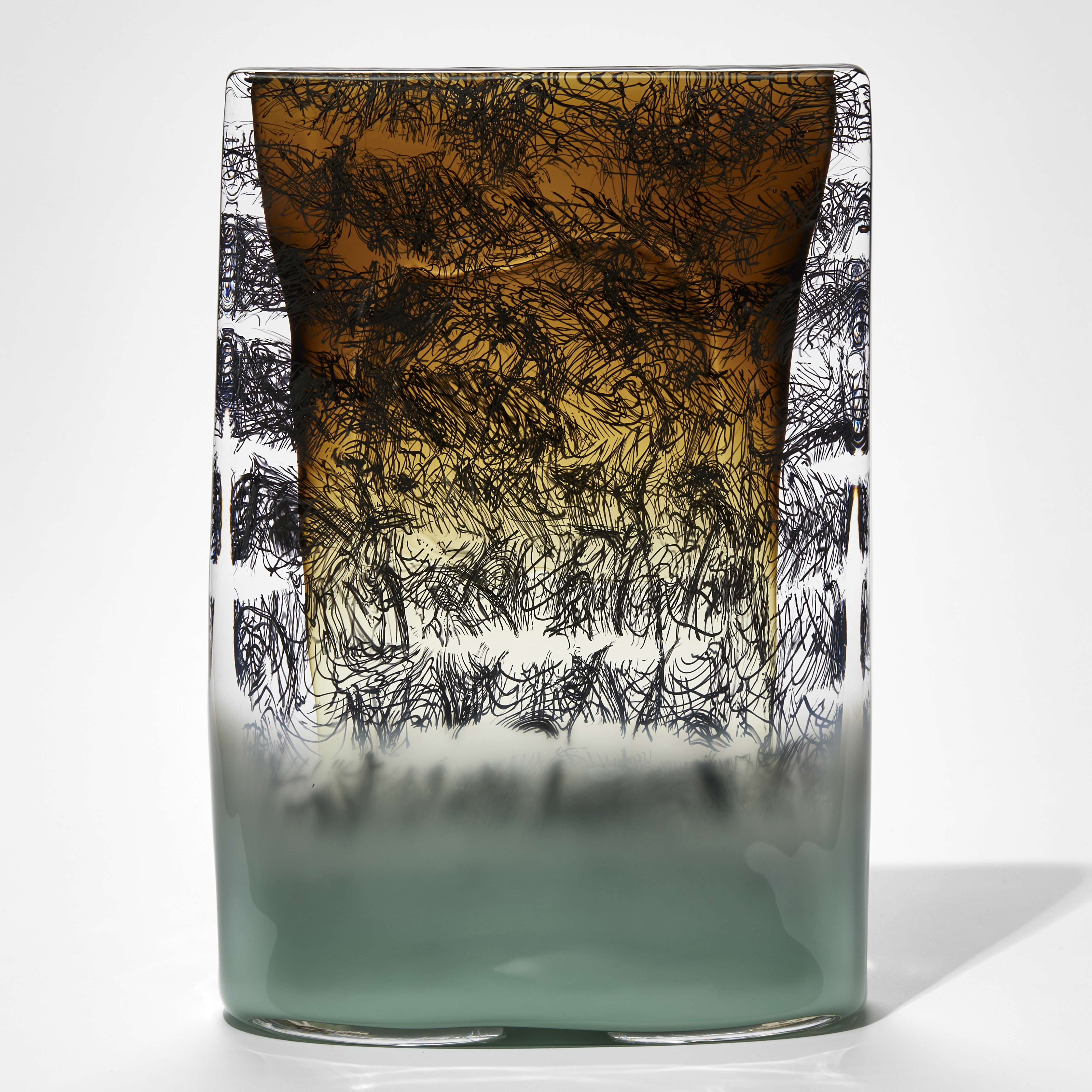 celadon green and amber sone tablet shaped sculpture with black wiggly lines text handmade from glass