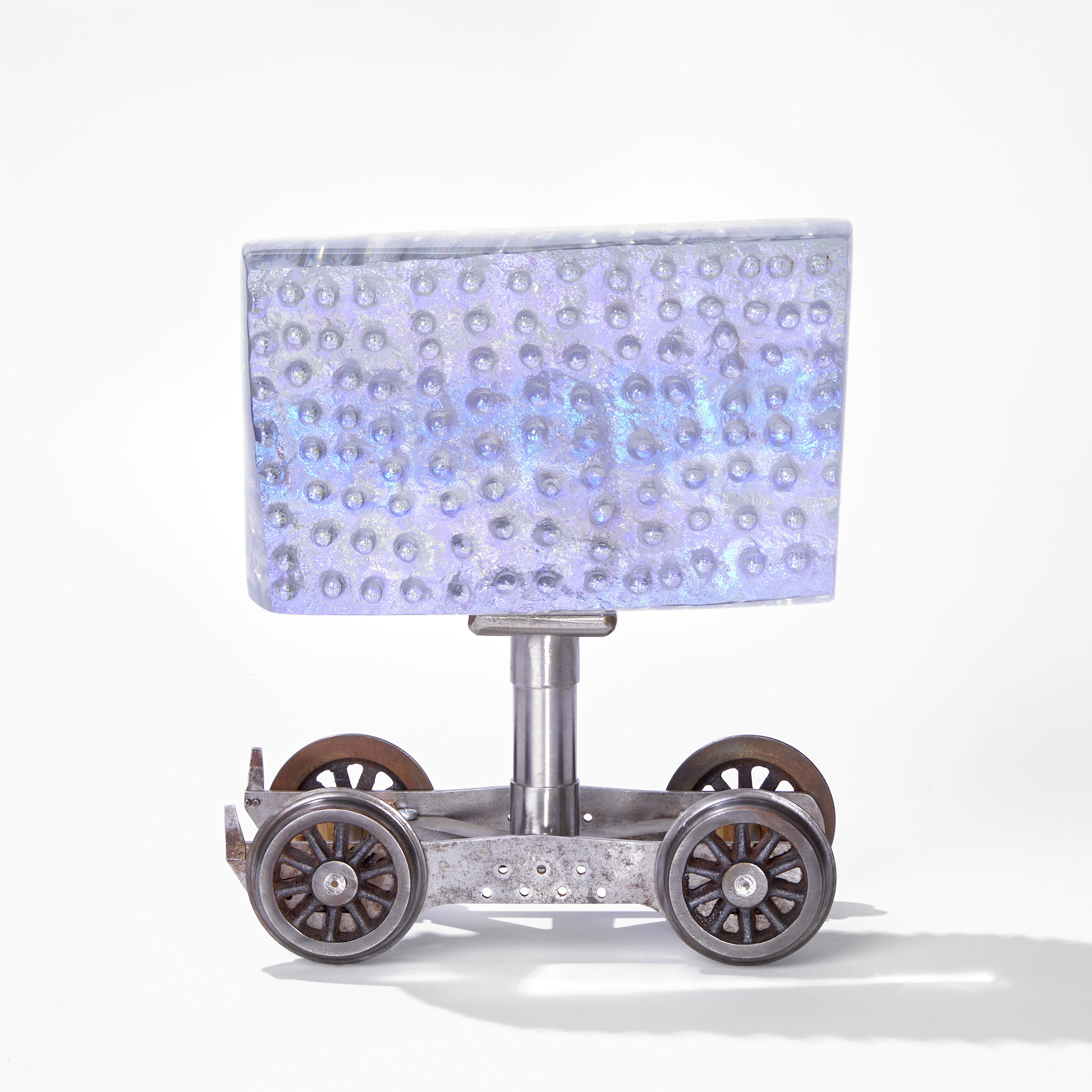 clear rectangular block of cast glass with rasied dimples attached to a scale model rolling stock bogie 