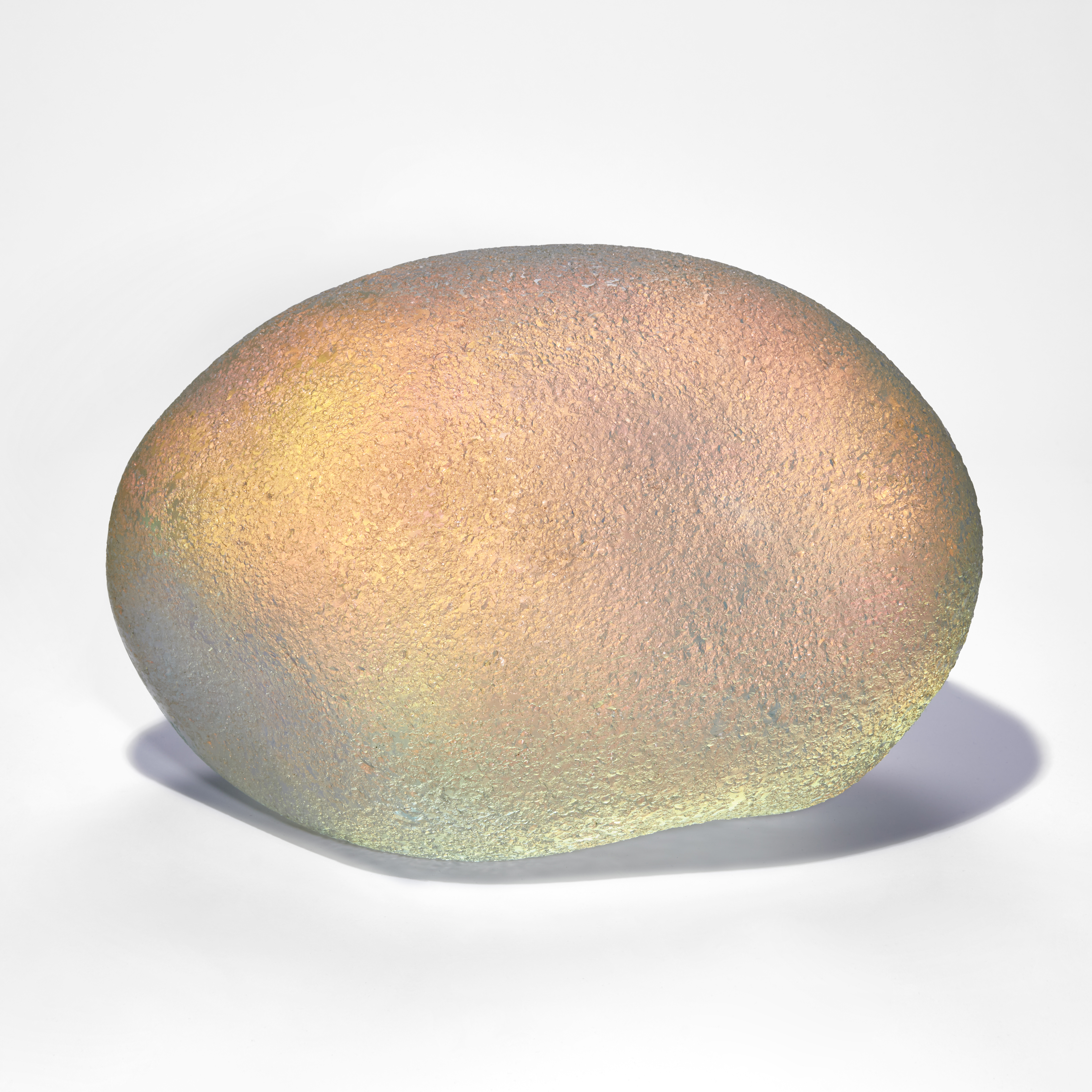 iridescent and gold coloured ovoid handmade glass sculpture with soft rock like texture
