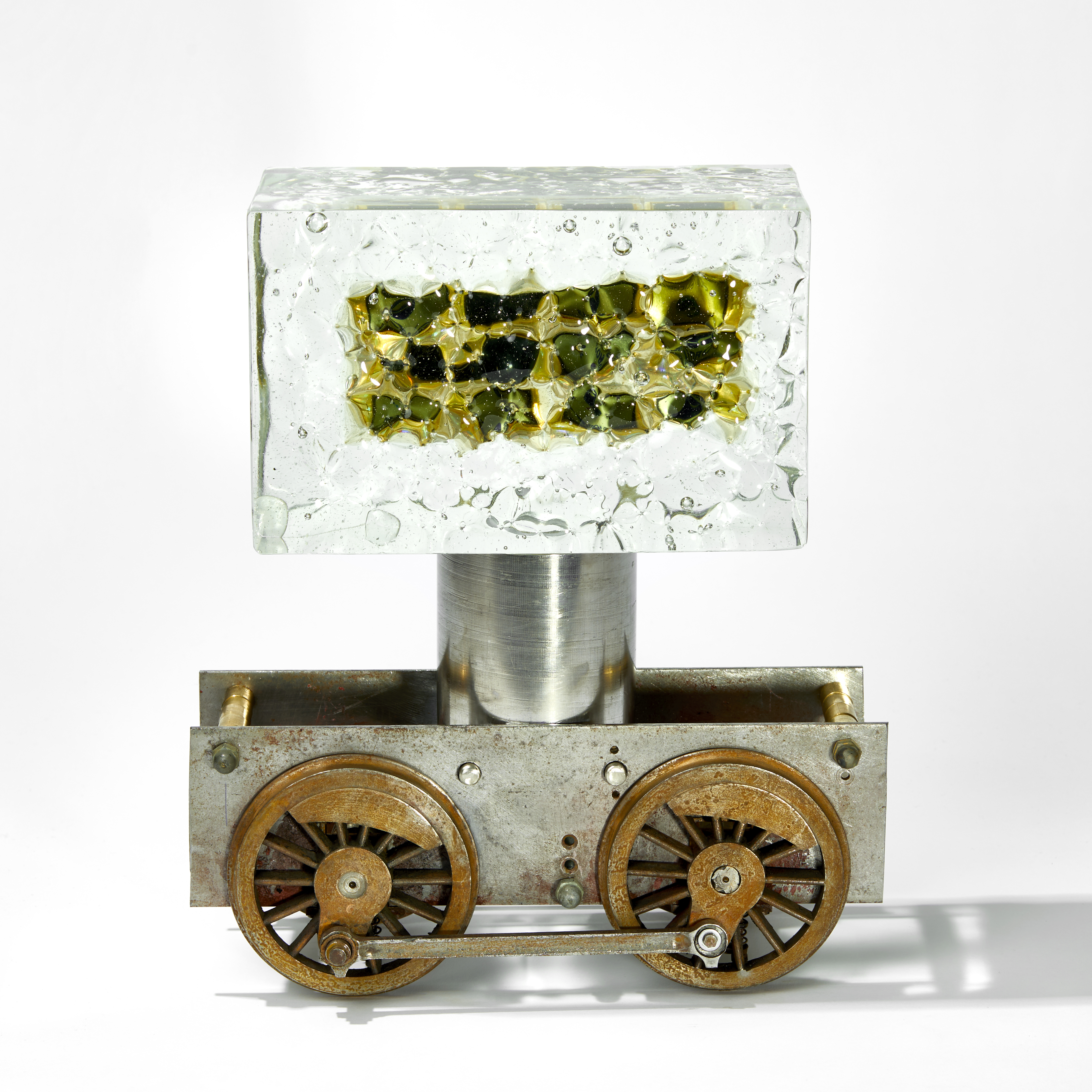 chunky ages metal train chassis with solid rectangular mass of glass above with inner winking eyes handmade from glass 
