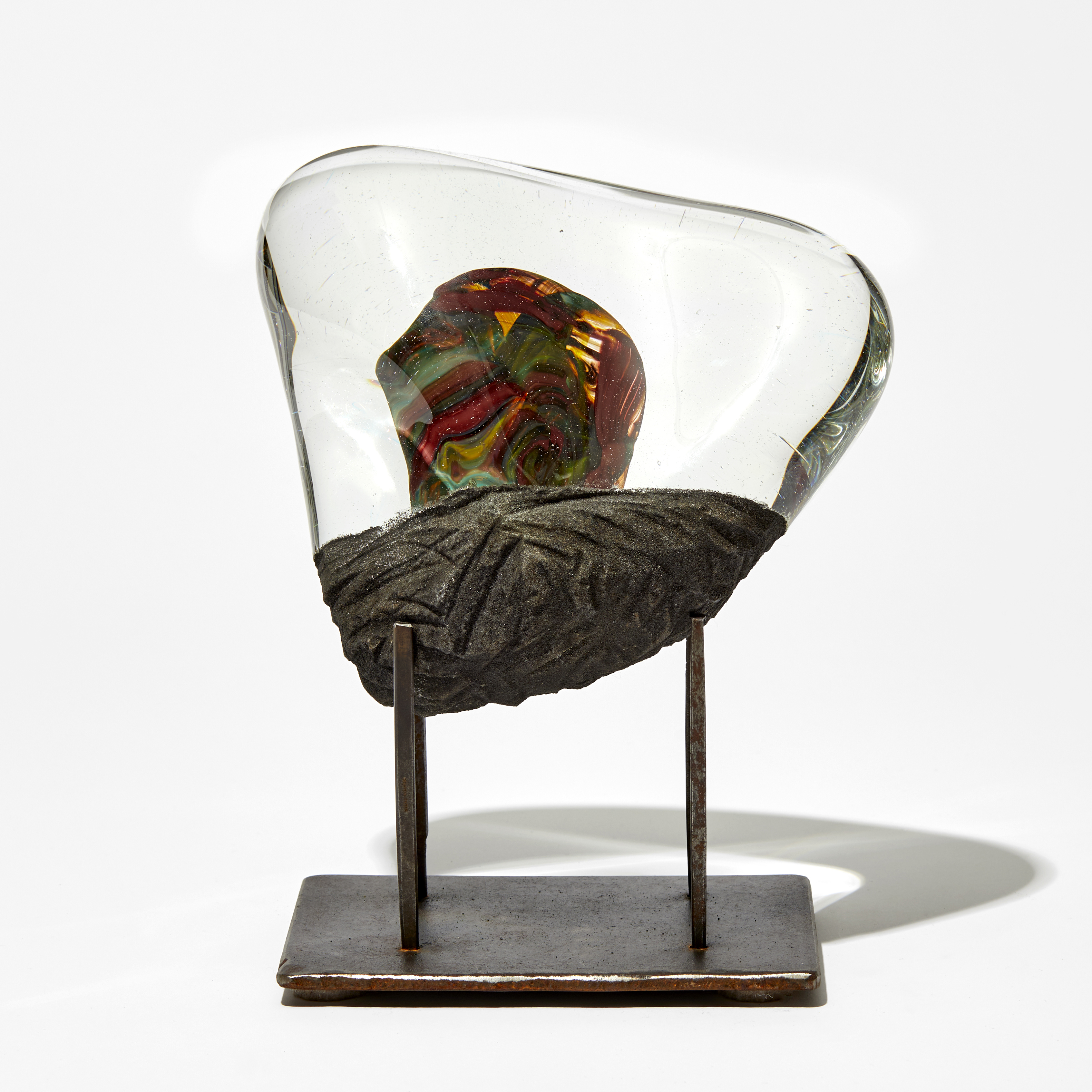 triangular clear and matt grey sculpture with inner blob detail in red and yellow handmade from glass on a steel base