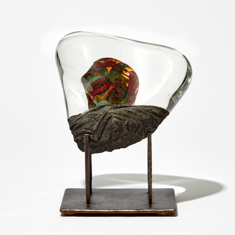 triangular clear and matt grey sculpture with inner blob detail in red and yellow handmade from glass on a steel base