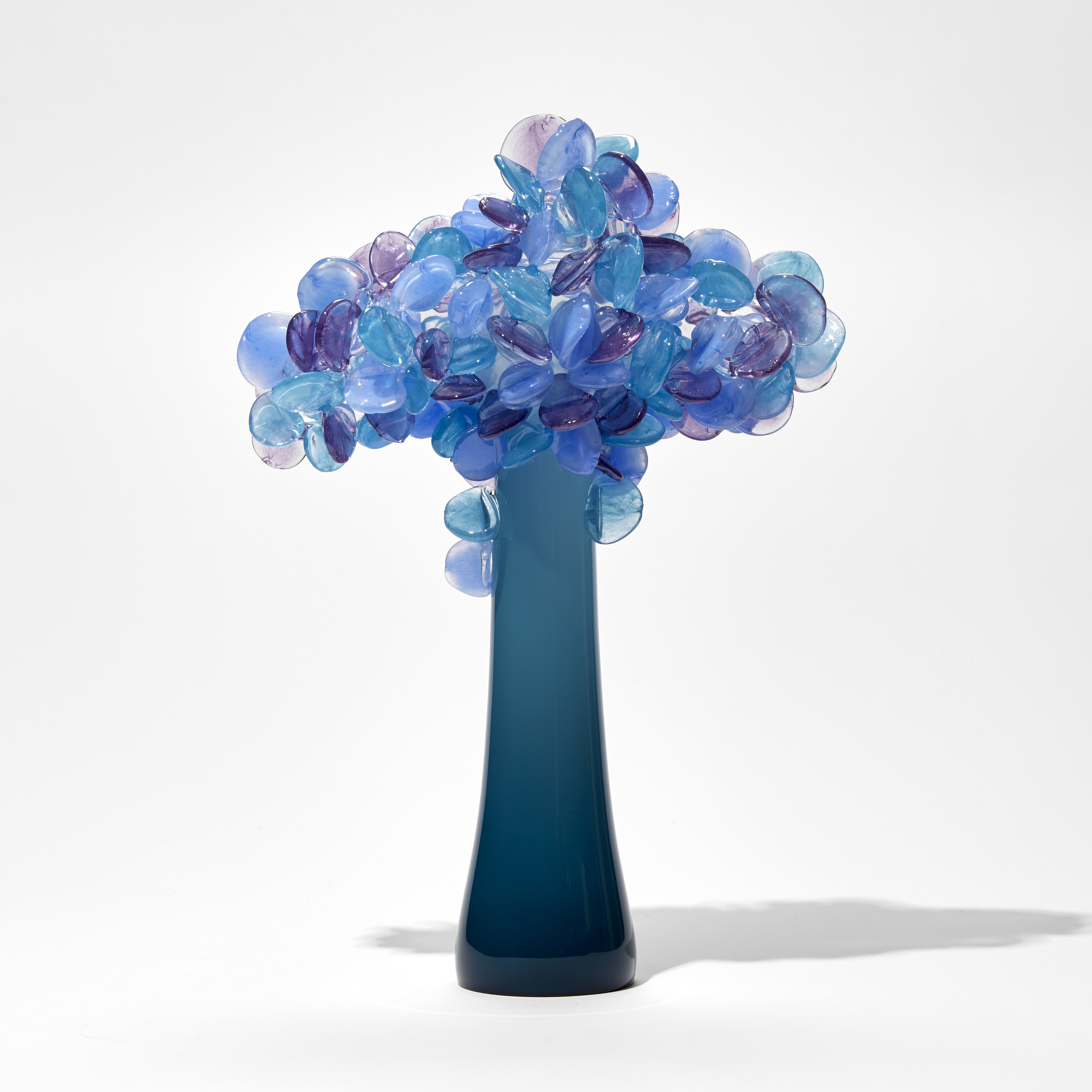deep teal sculptural tree with simplified lollipop shaped leaves in blues purples and pinks handmade from glass