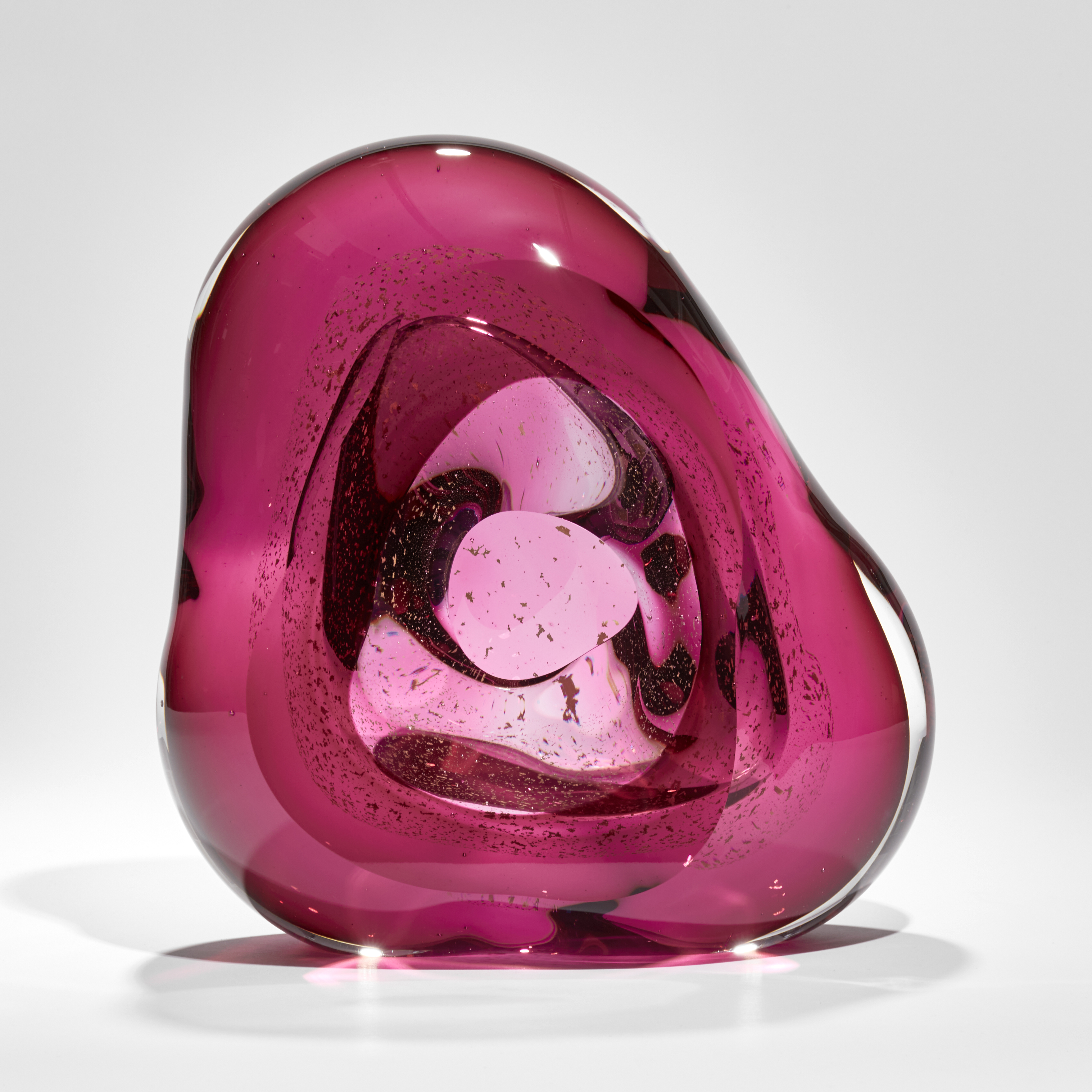 blobby pink mass of glass with central hole and swirling mass of trapped small fragments of glass