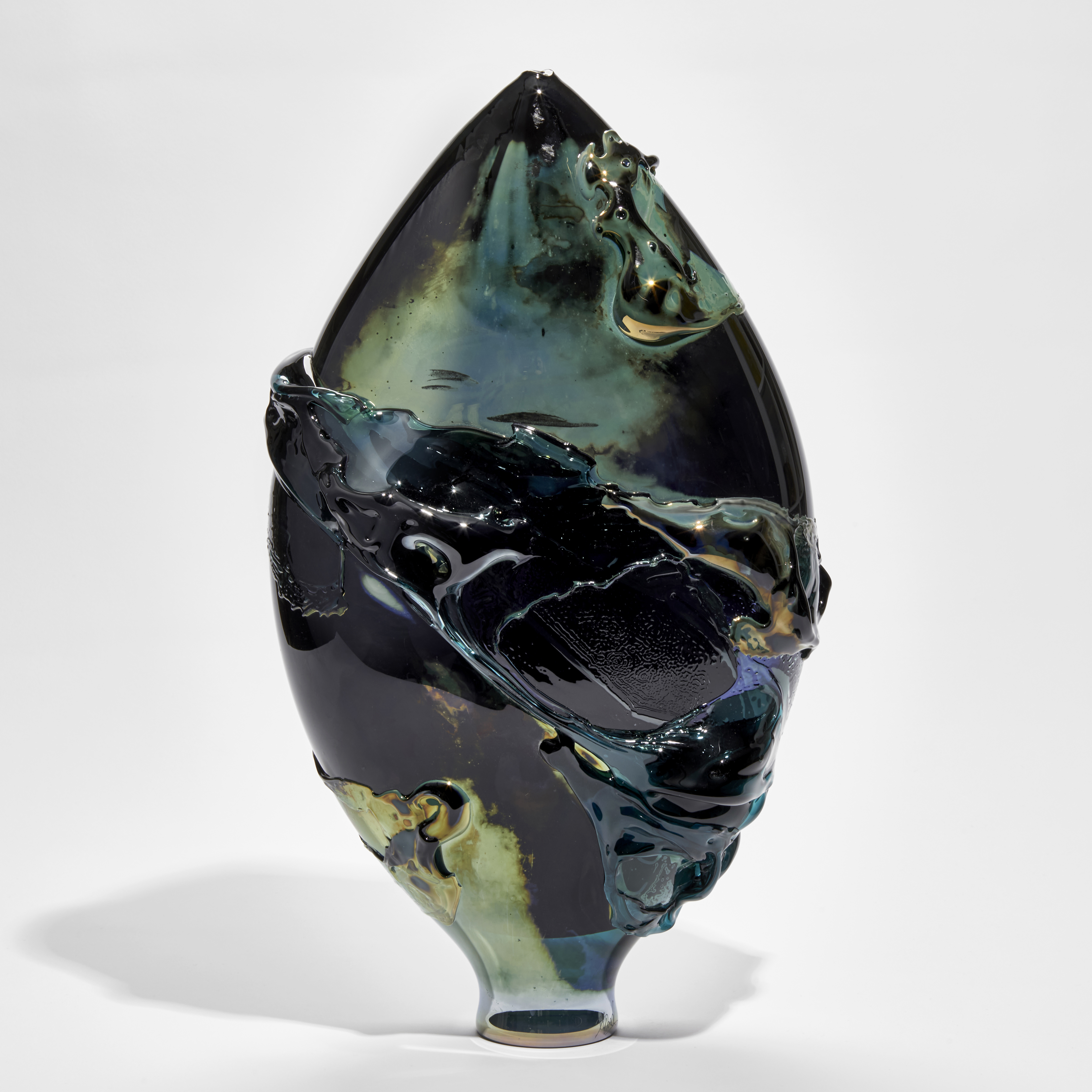 black blue and green lustrous oval vessel with organic smeared texture across the surface handmade from glass