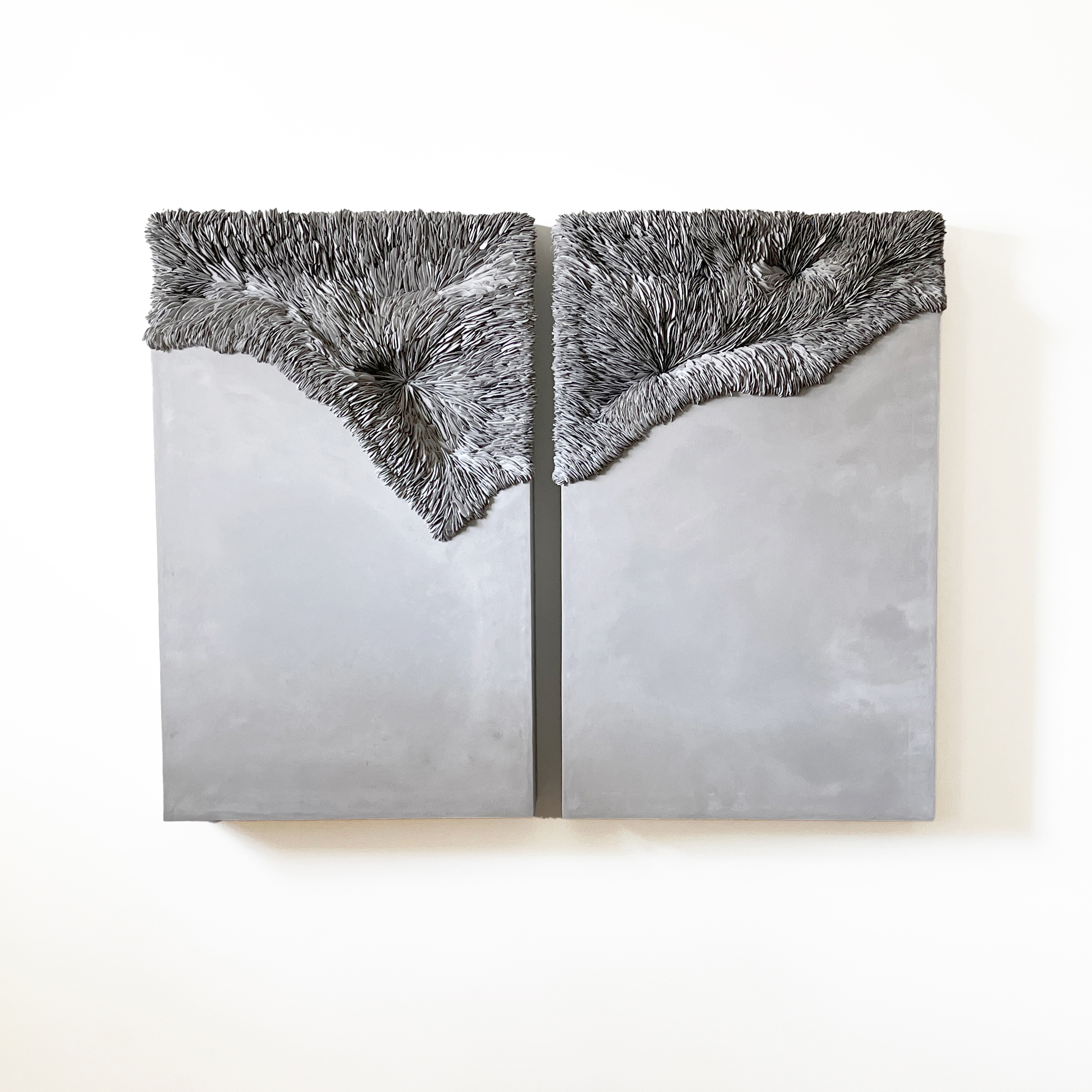 twinned wall mounted rectangular artworks with smooth areas moving to highly textured sections created from ridged shards of porcelain